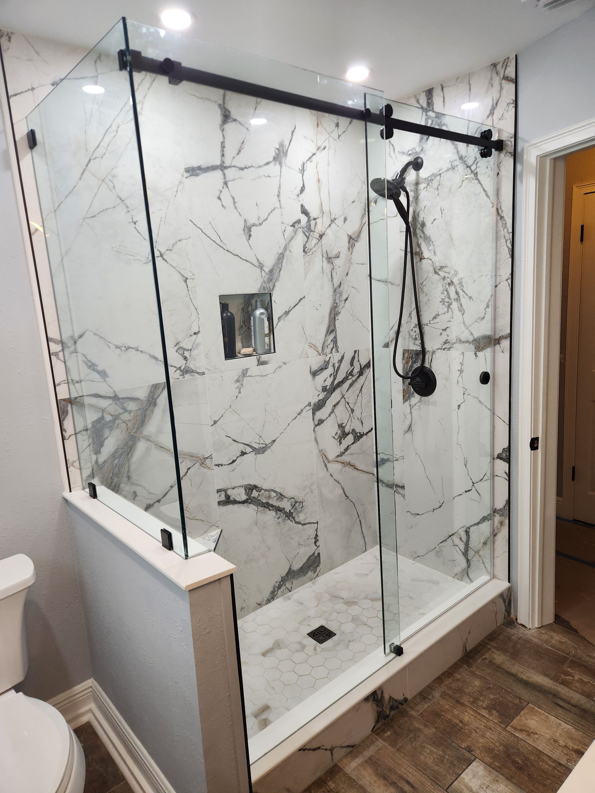 a bathroom with a sliding glass shower door and marble walls