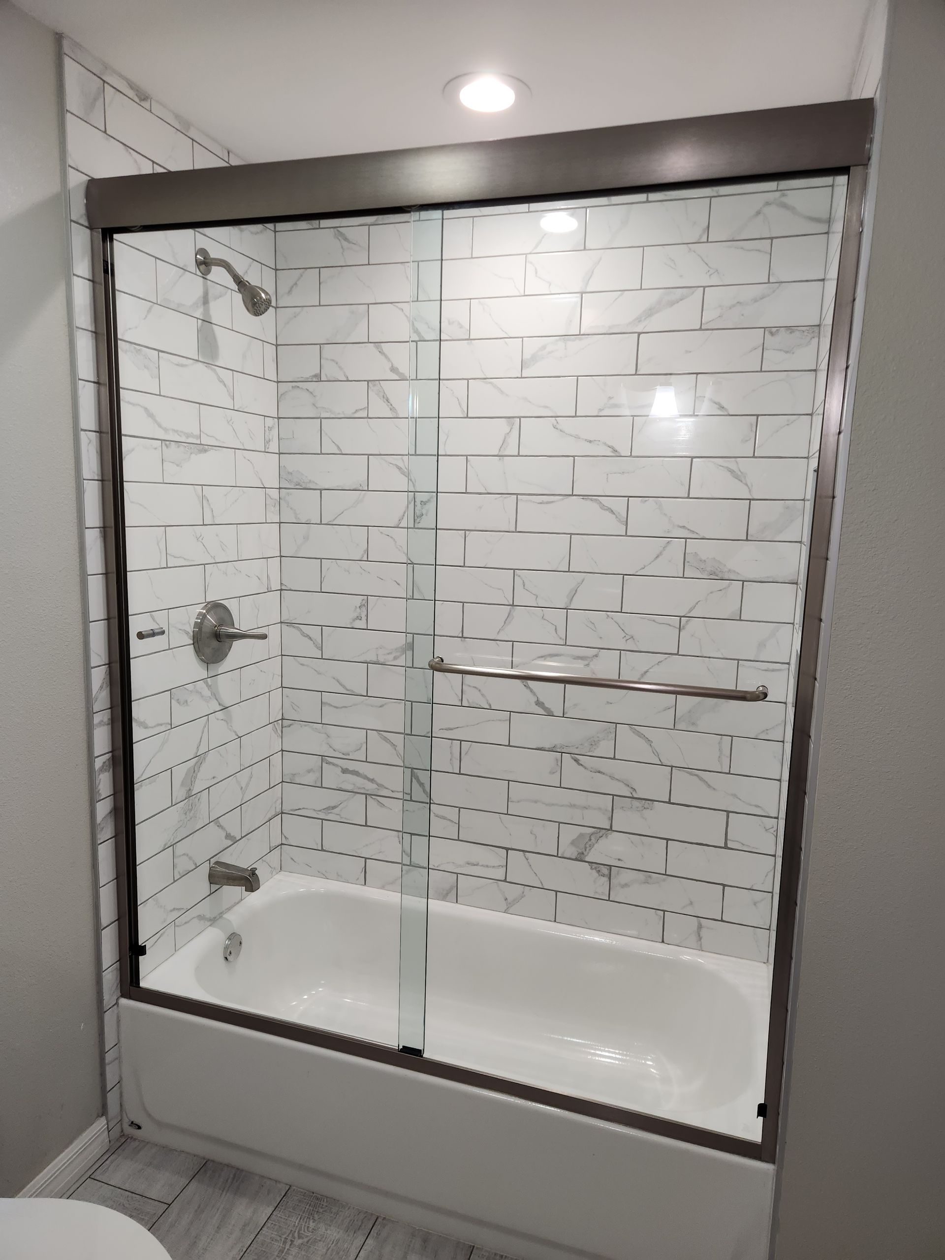 a bathroom with a bathtub and a shower with a sliding glass door