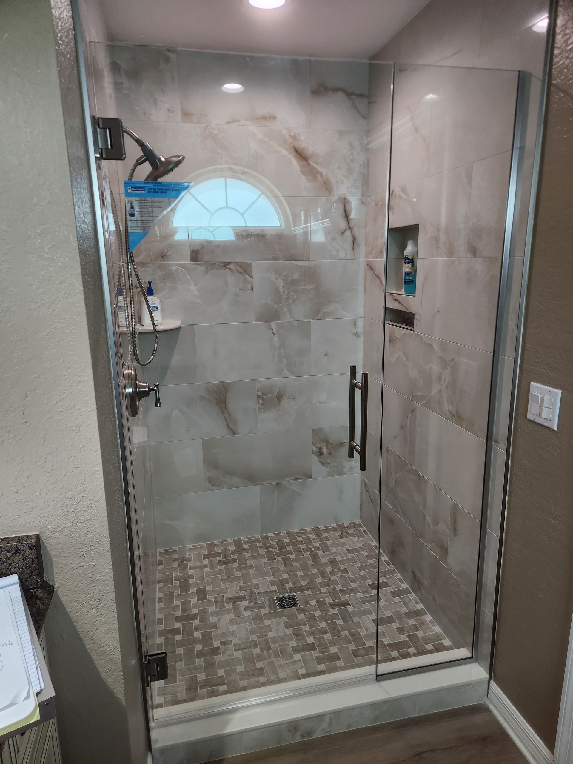 A bathroom with a walk in shower with a glass door.