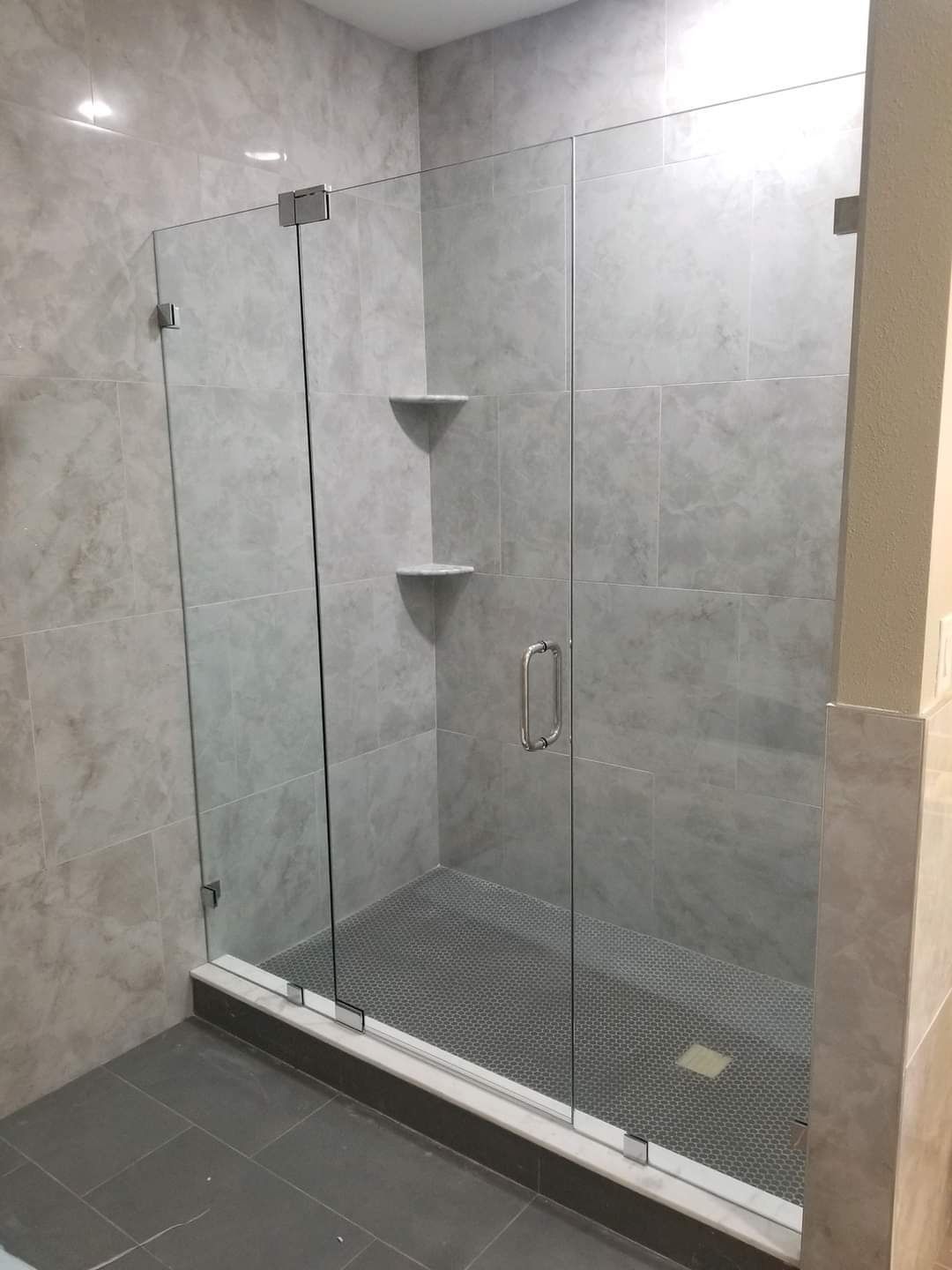 Glass shower enclosure with gray tile walls and floor.