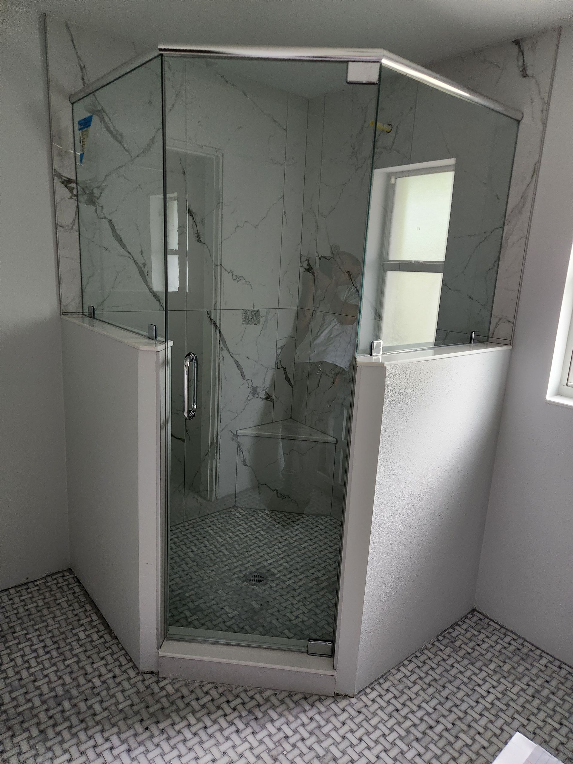 A bathroom with a shower stall and a window.