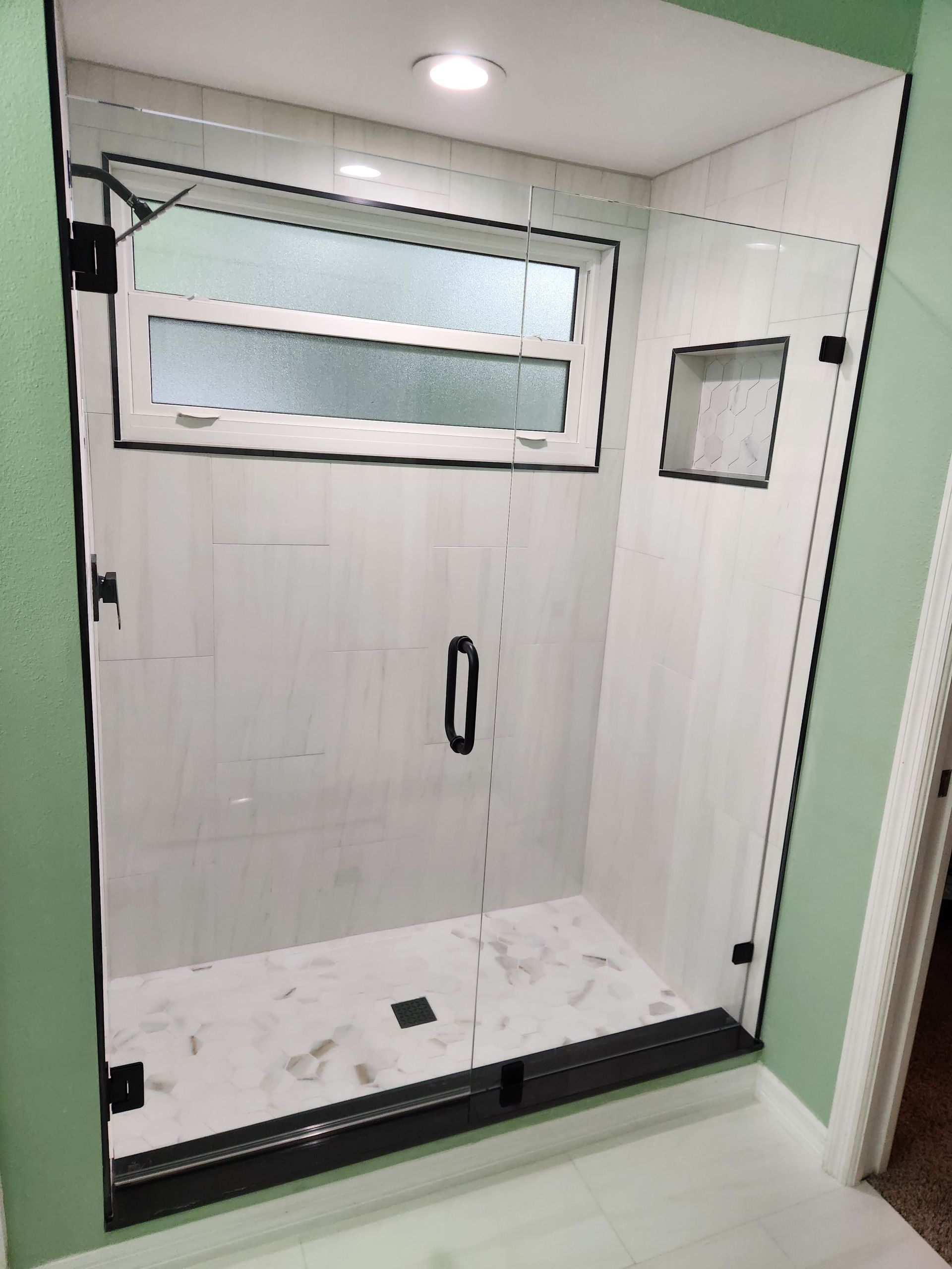 a shower with a glass door and a window
