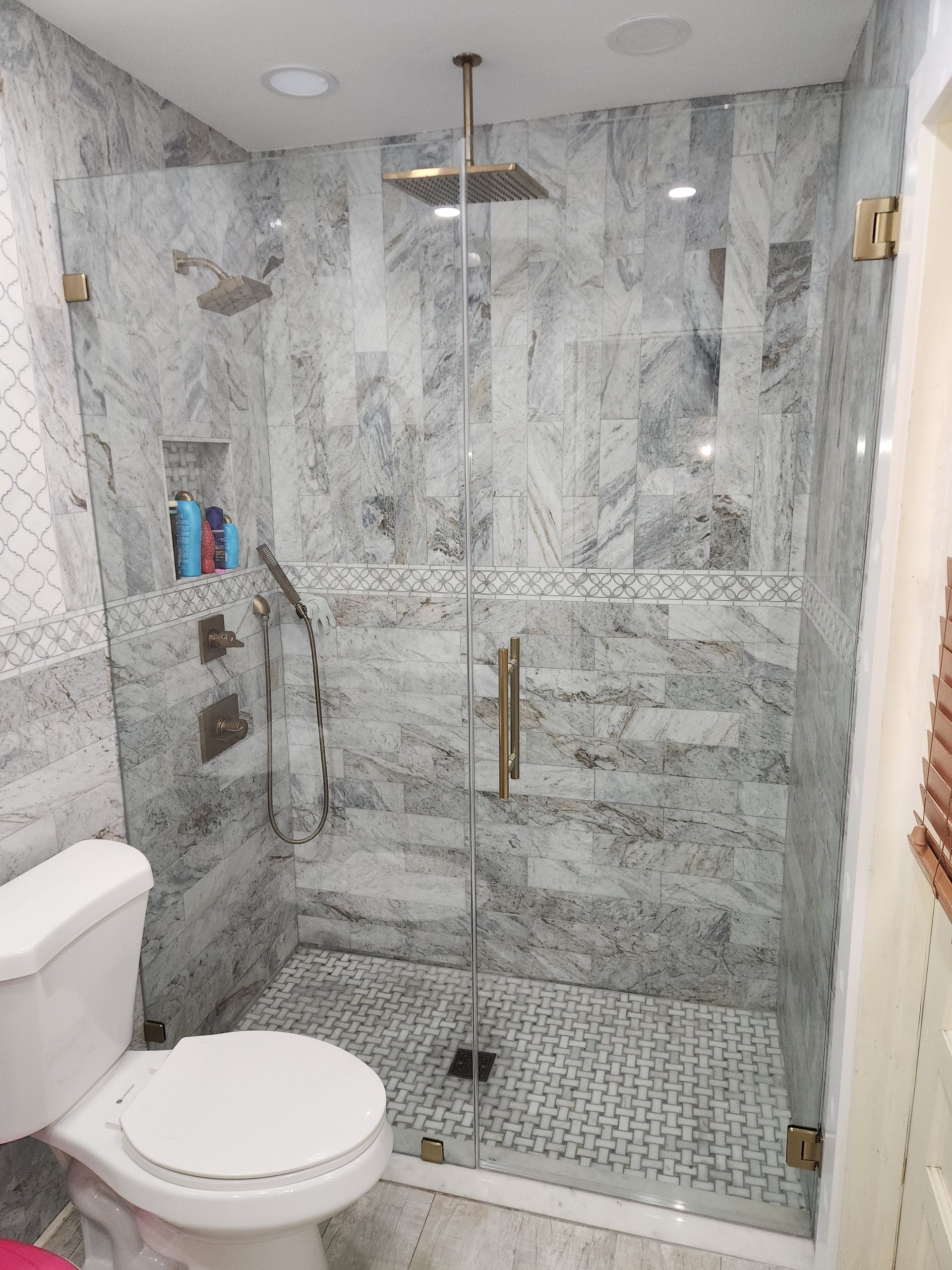 a bathroom with a toilet and a walk-in shower with a glass door