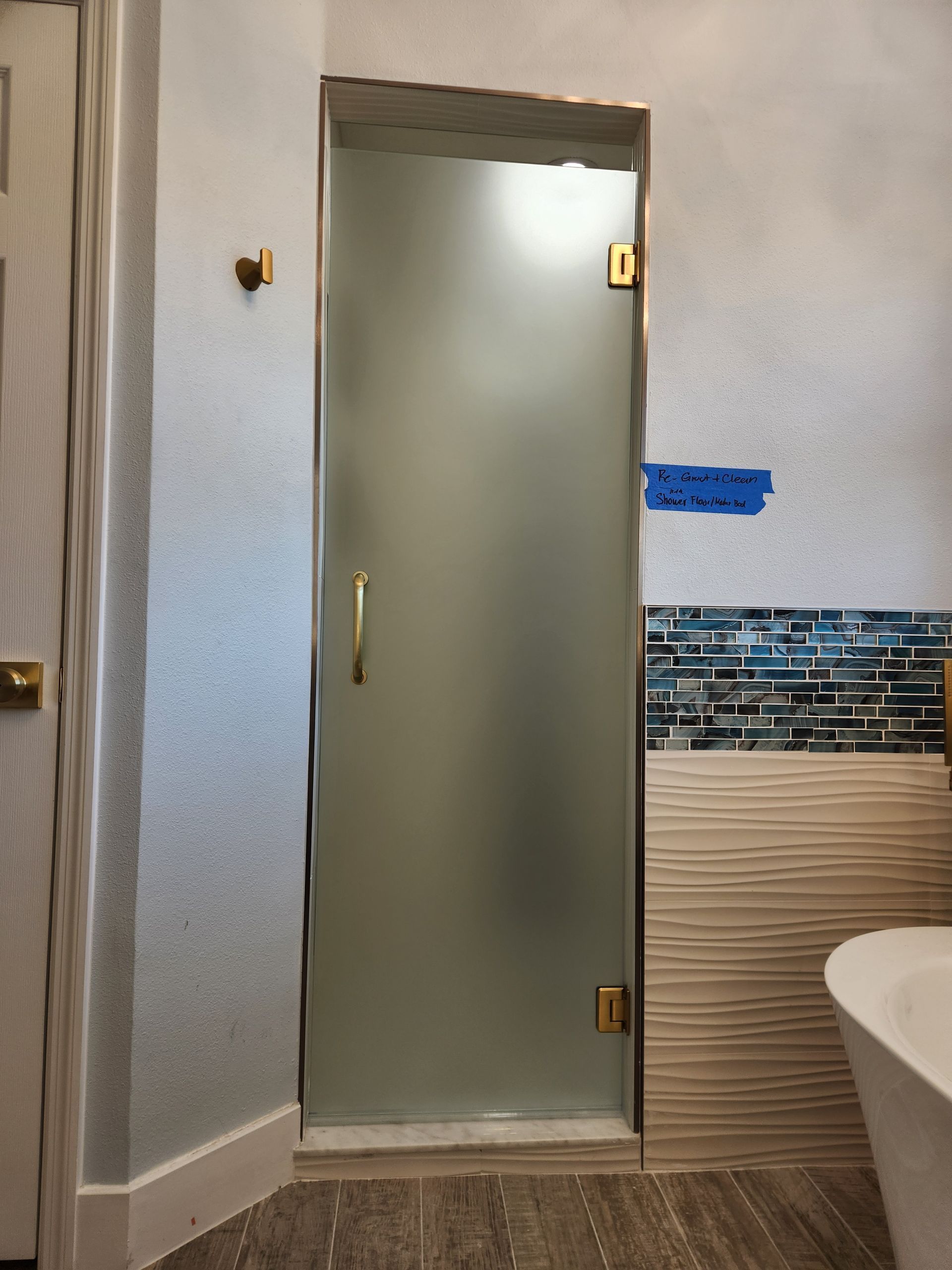 a bathroom with a bathtub and a frosted glass shower door