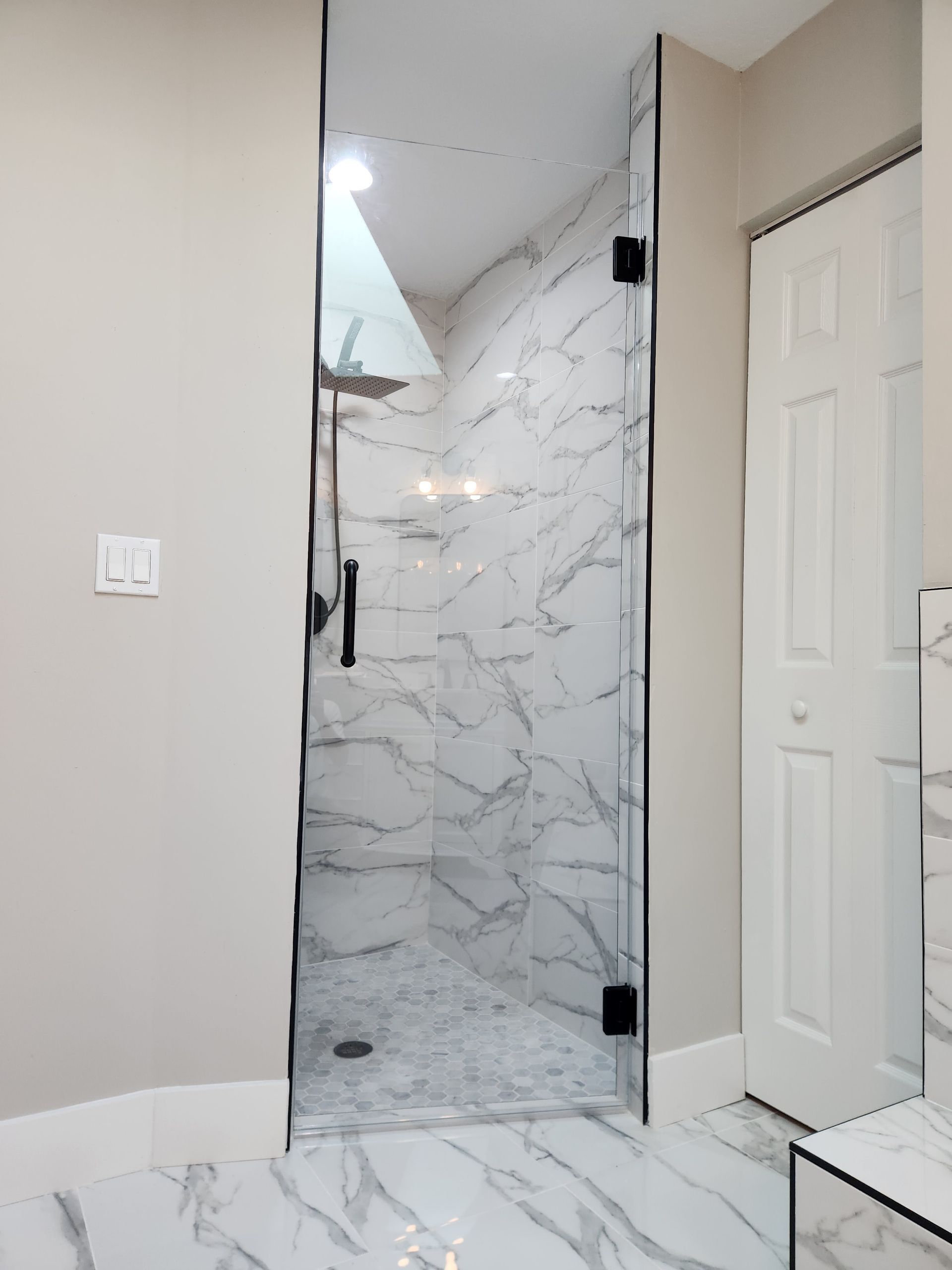a bathroom with marble tiles and a walk-in shower with a glass door