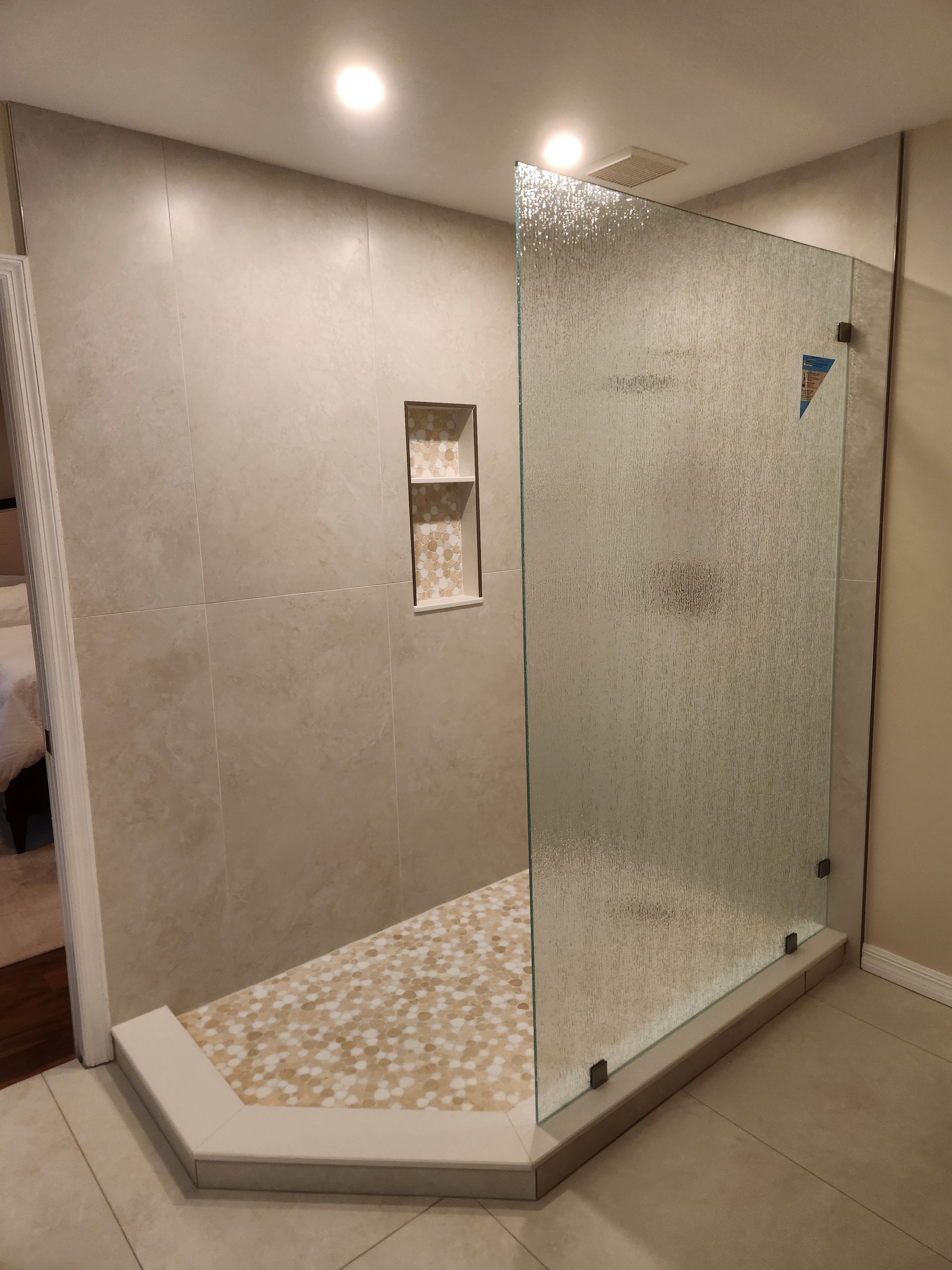 A bathroom with a walk in shower with a glass door.