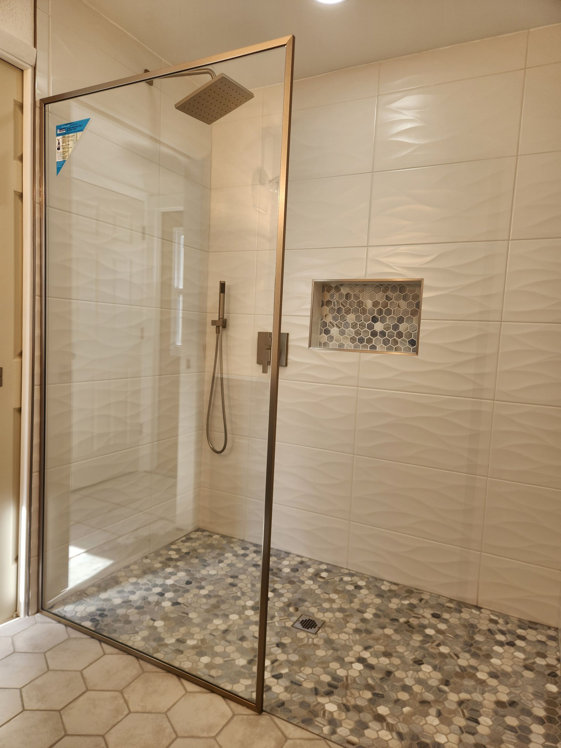A walk in shower with a glass door and a shower head.
