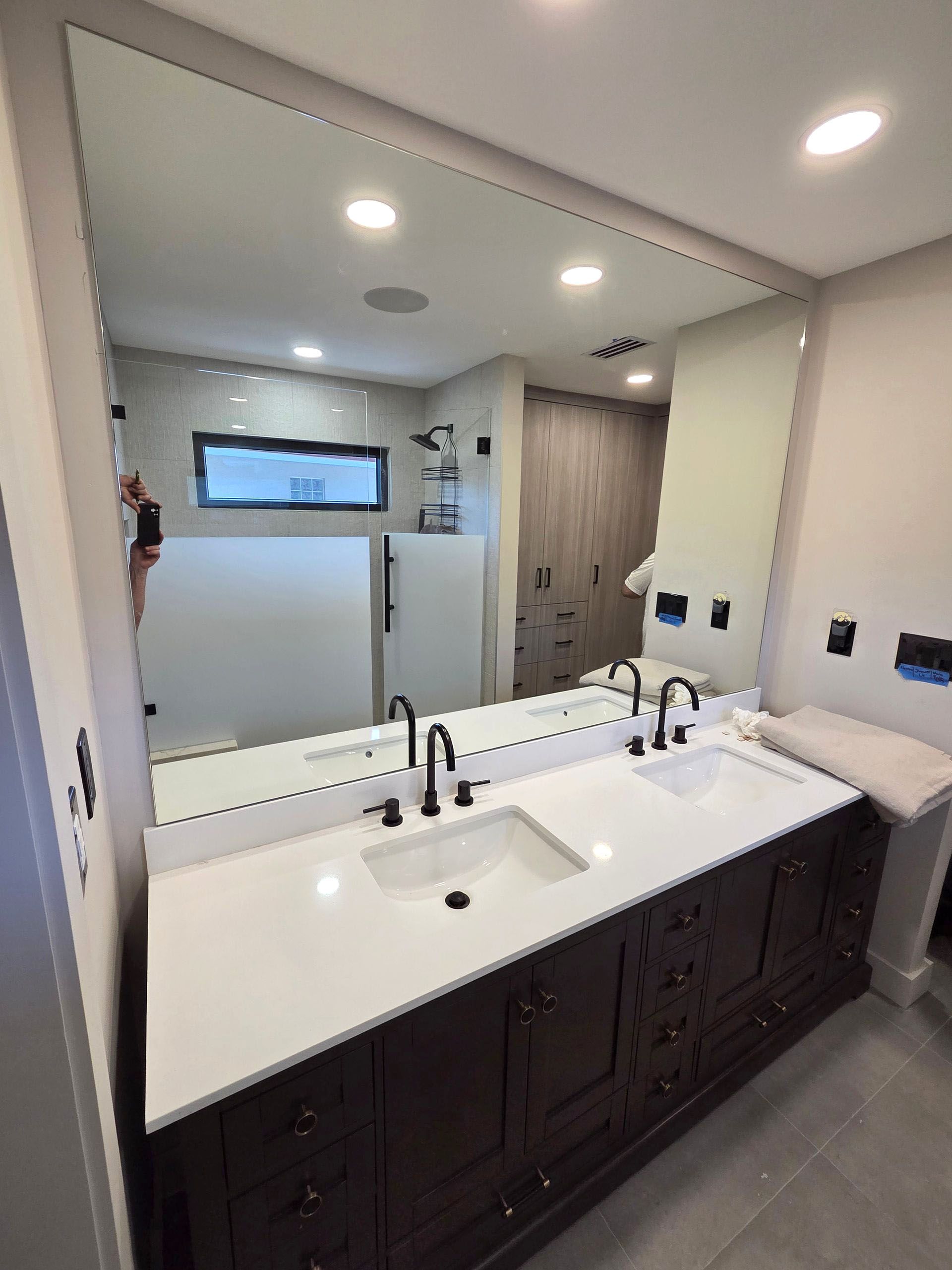 Modern bathroom vanity with double sinks, large custom-made mirror, and gray tile floor