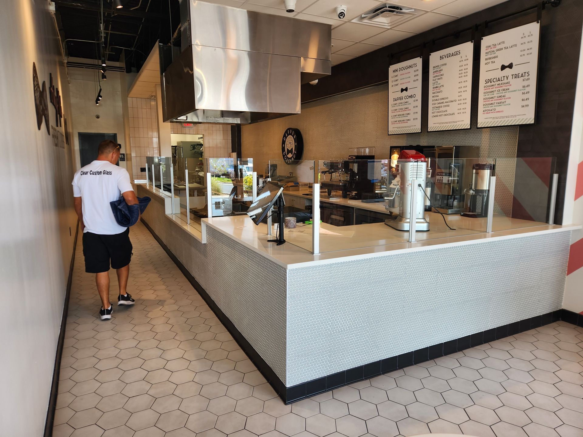 Modern cafe counter with menu boards and a customer ordering at the register