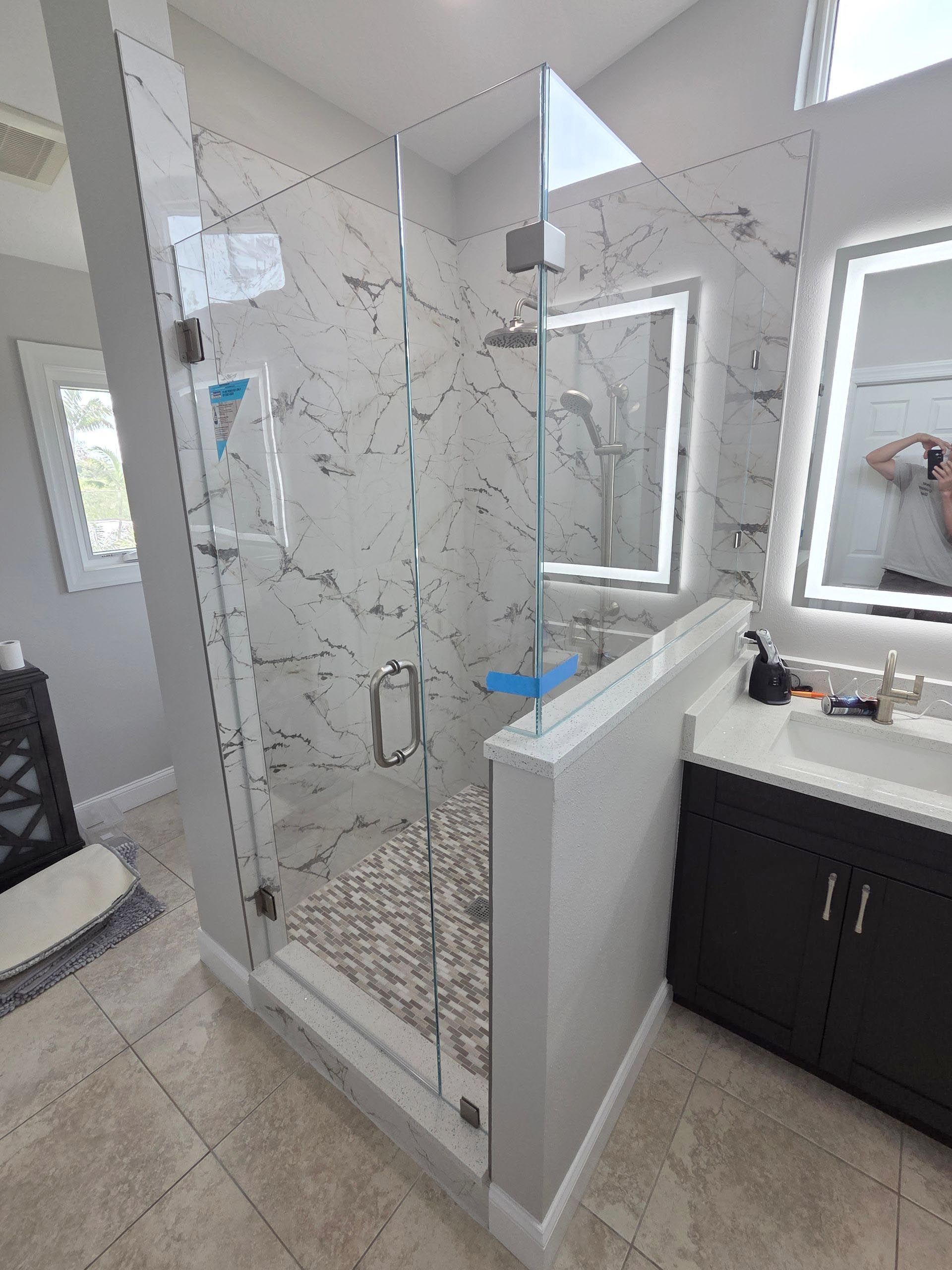 Modern bathroom with glass shower enclosure, white vanity, and gray tile flooring