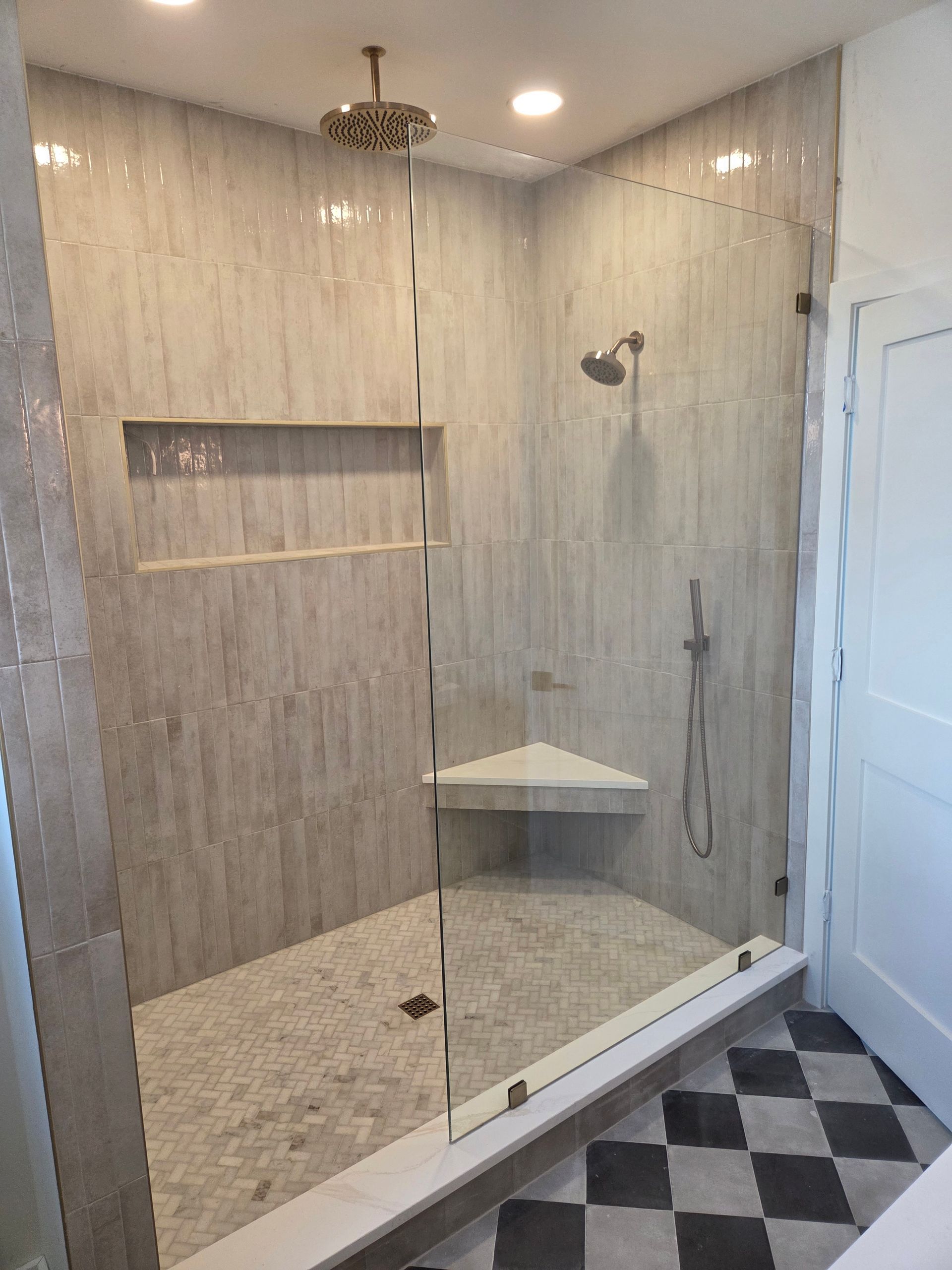 Modern bathroom with tiled walk-in shower, glass door, wall niche, and hexagon floor tiles