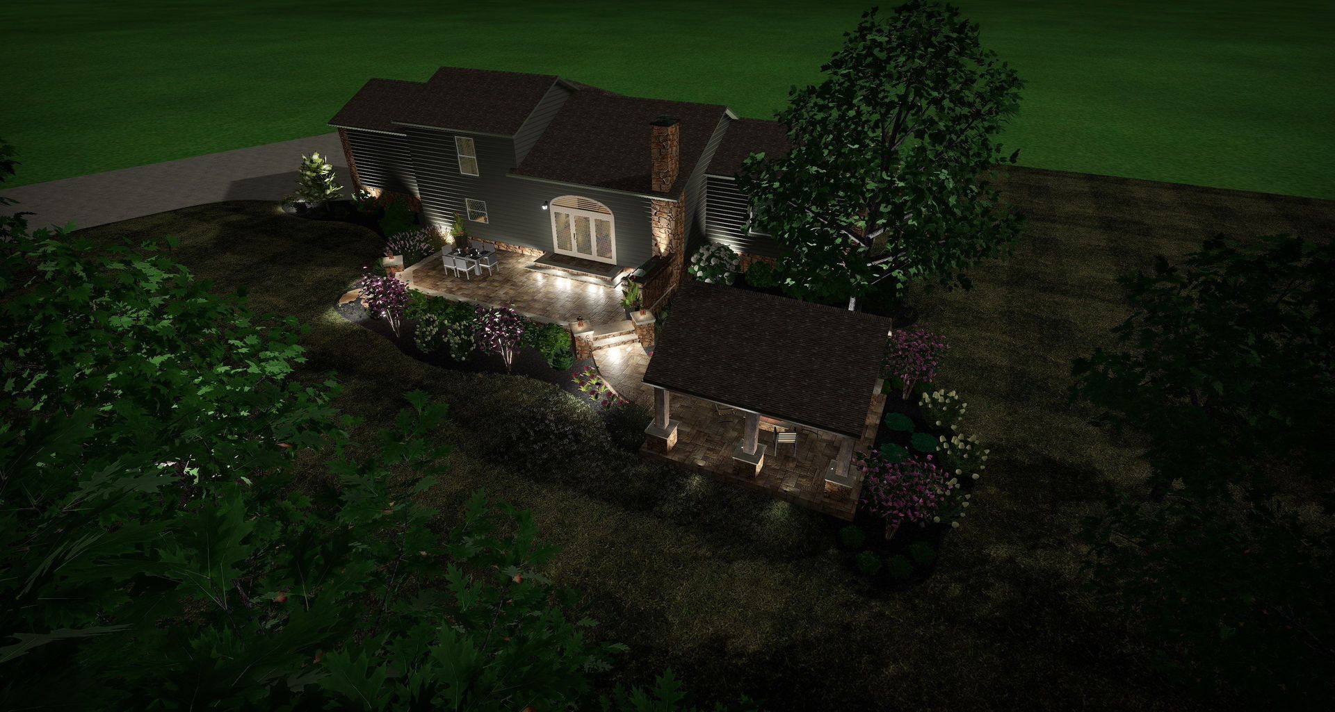 Nighttime view of a lit two-story house with a porch, surrounded by trees and lawn.
