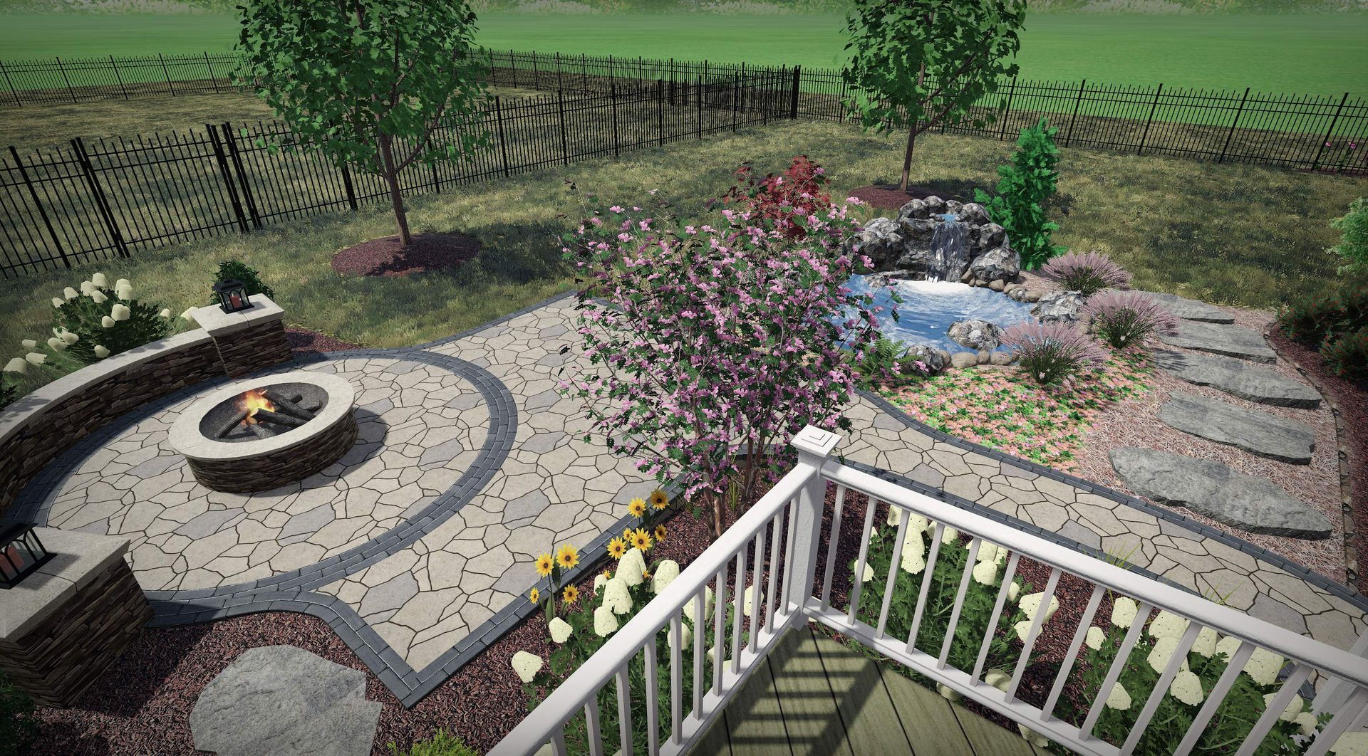 Stone patio with circular fire pit, gravel border, flowering shrubs, and a white railing overlooking a yard