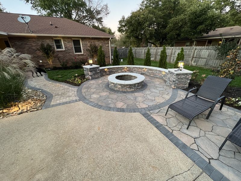 Backyard patio with a stone fire pit, curved wall, and pavers.