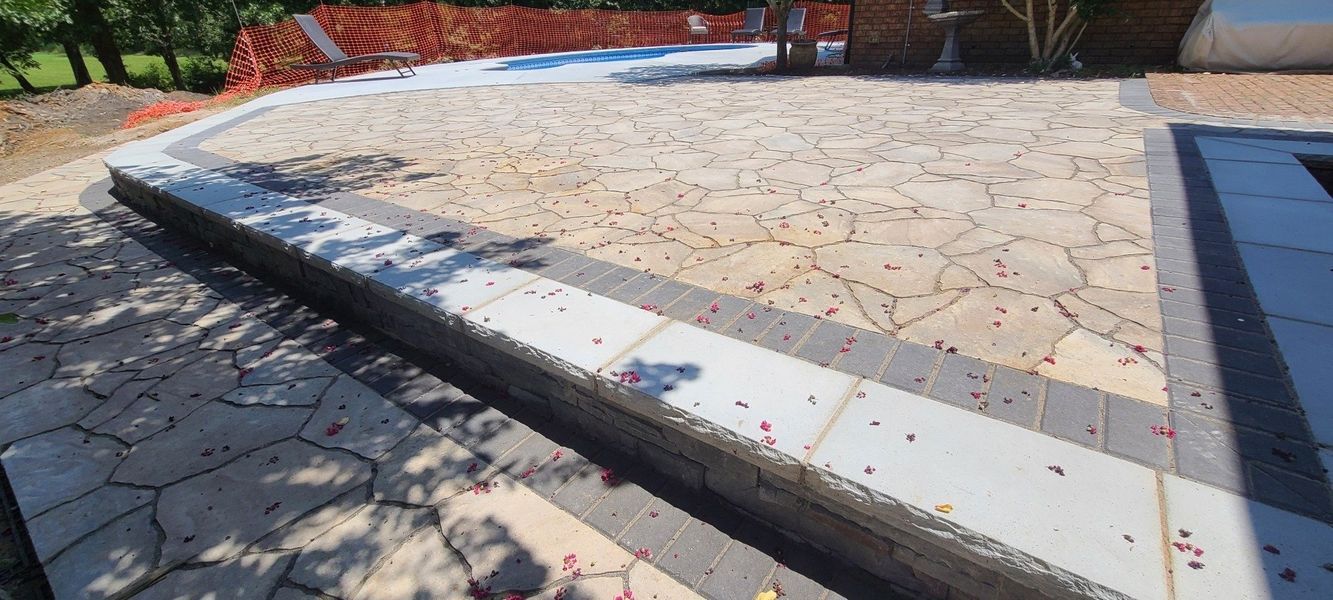 Stone patio with a low retaining wall and border. Construction site.