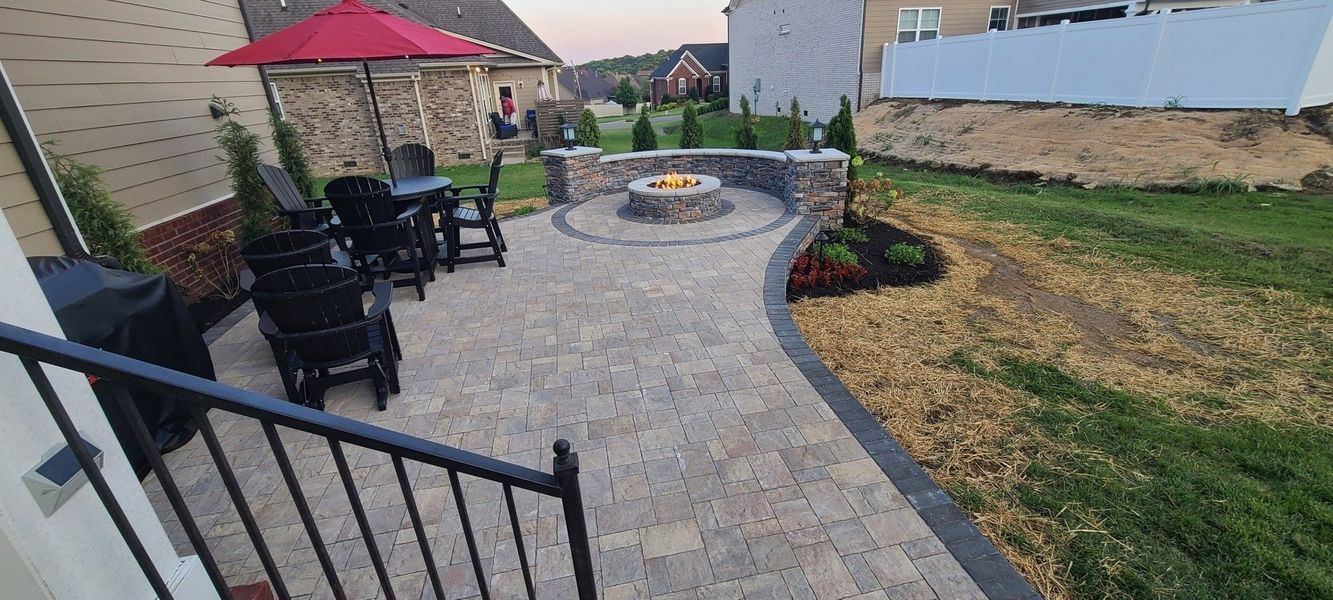 Backyard patio with fire pit, seating area, and green lawn.