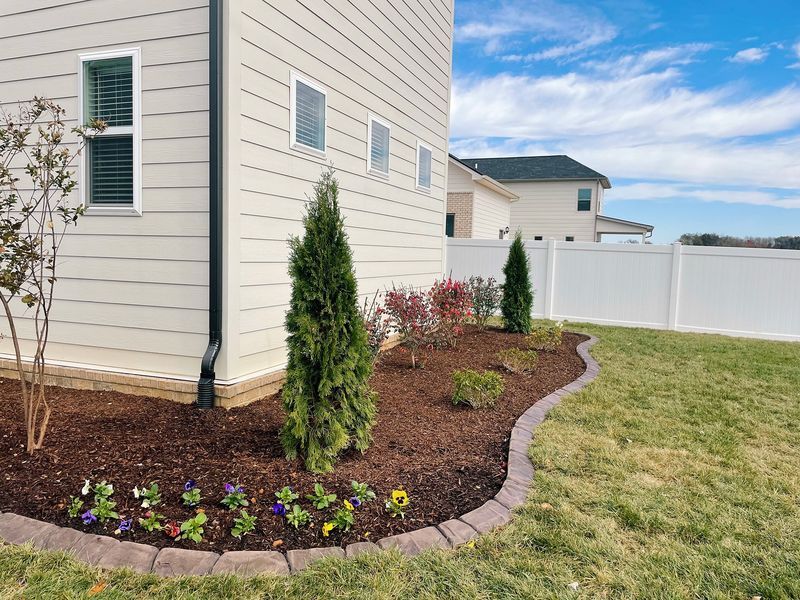 House exterior with a landscaped garden bed of plants, mulch, and a stone border.
