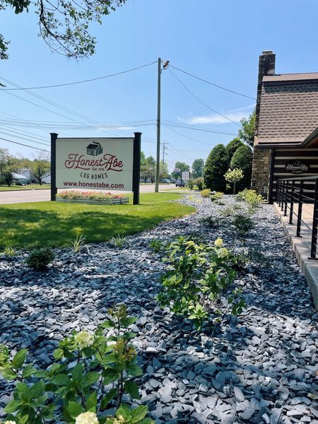 Sign for Haven Rose, a restaurant with a flower bed, on a sunny day.