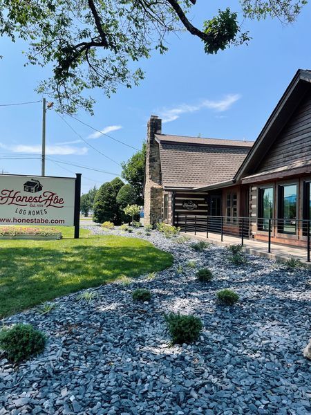 Sign for Honest Abe's restaurant with a stone and log building on a sunny day.
