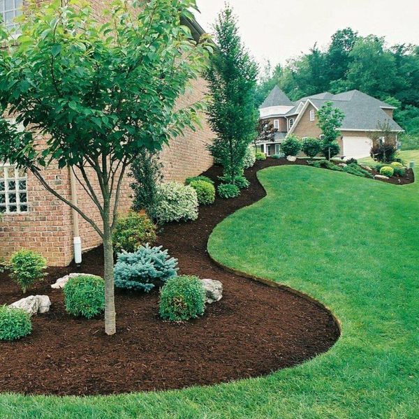 Well-manicured lawn with mulched flower beds, trees, shrubs, and a brick house.