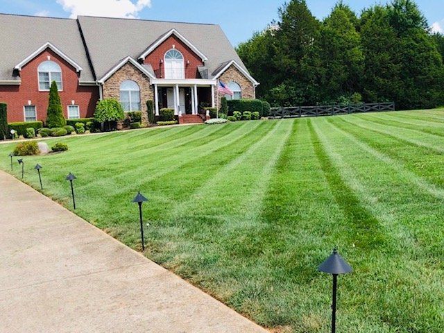 A house with a brick and stone facade and a freshly mowed lawn with decorative path lights.