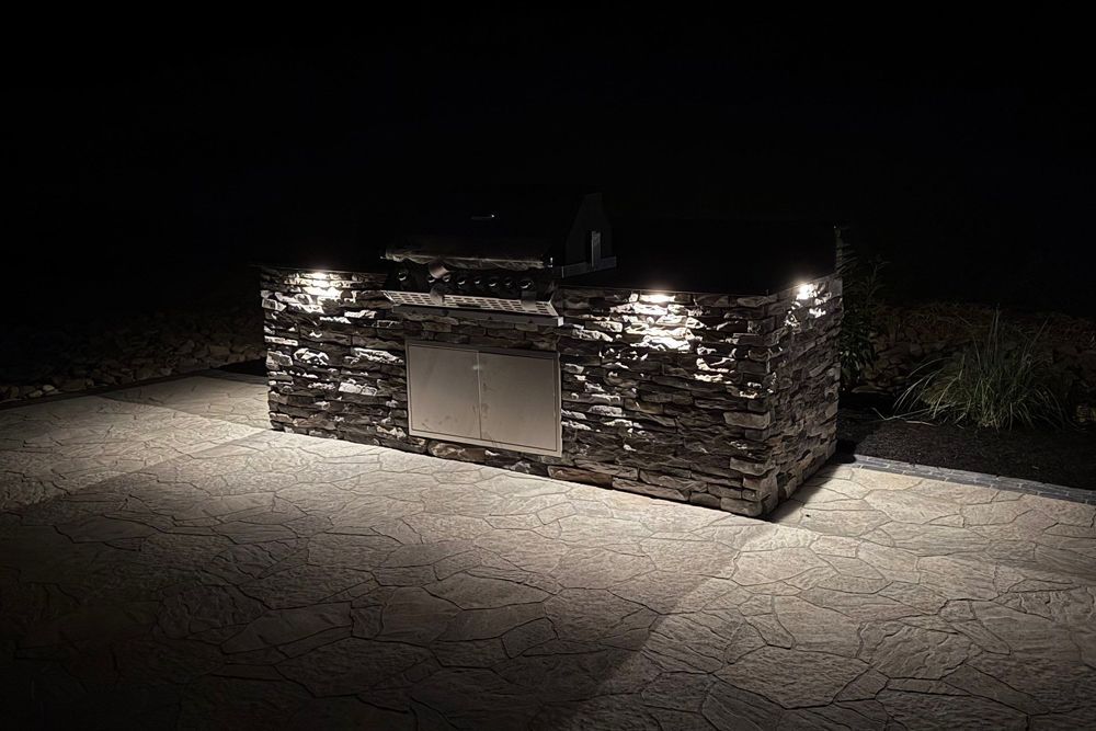 Outdoor kitchen with stone facade illuminated at night.