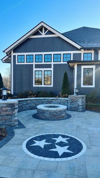 Tennessee flag emblem on paved patio with fire pit, home with dark gray siding.