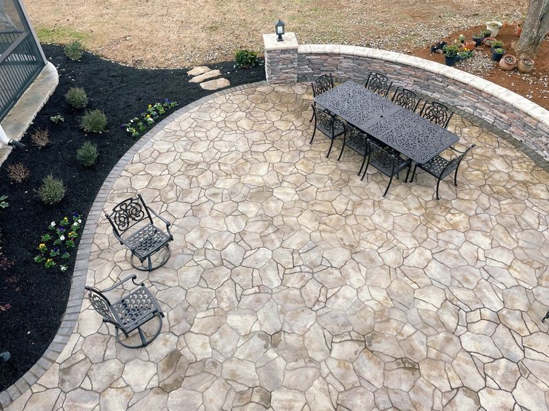 Patio with stone pavers, dining table, chairs, and landscaping with dark mulch.