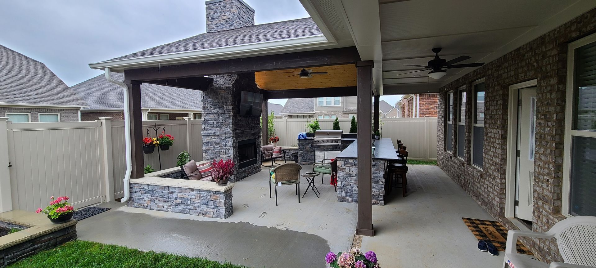 Outdoor patio with fireplace, grill, seating area, and surrounding fence.