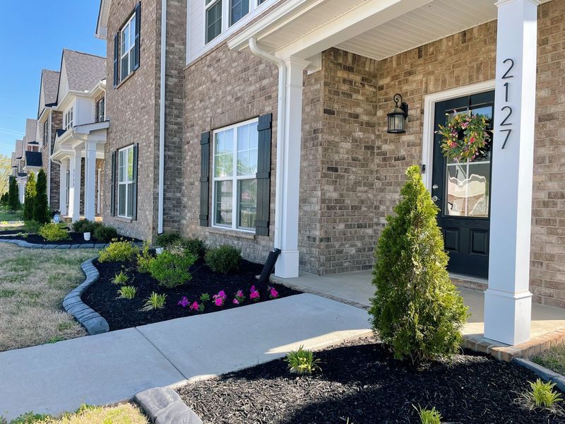Row of brick townhomes with landscaping and a door with a wreath at the address 2127.