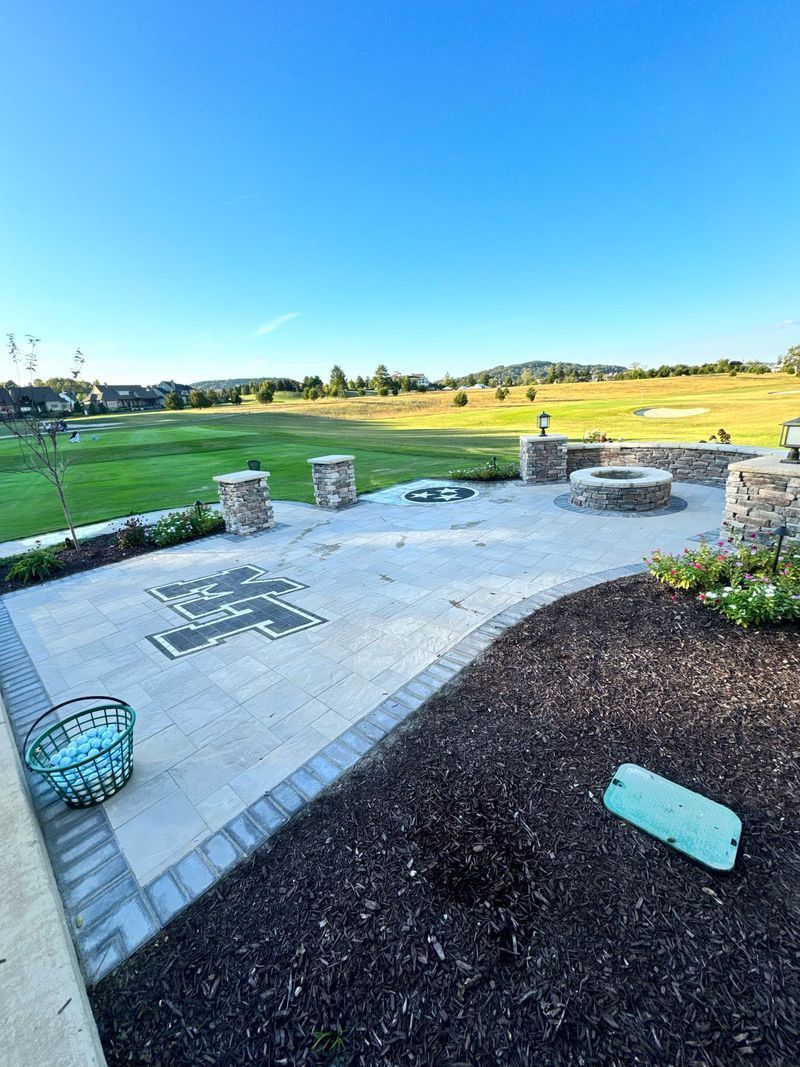 Patio with fire pits and view of a golf course on a sunny day.