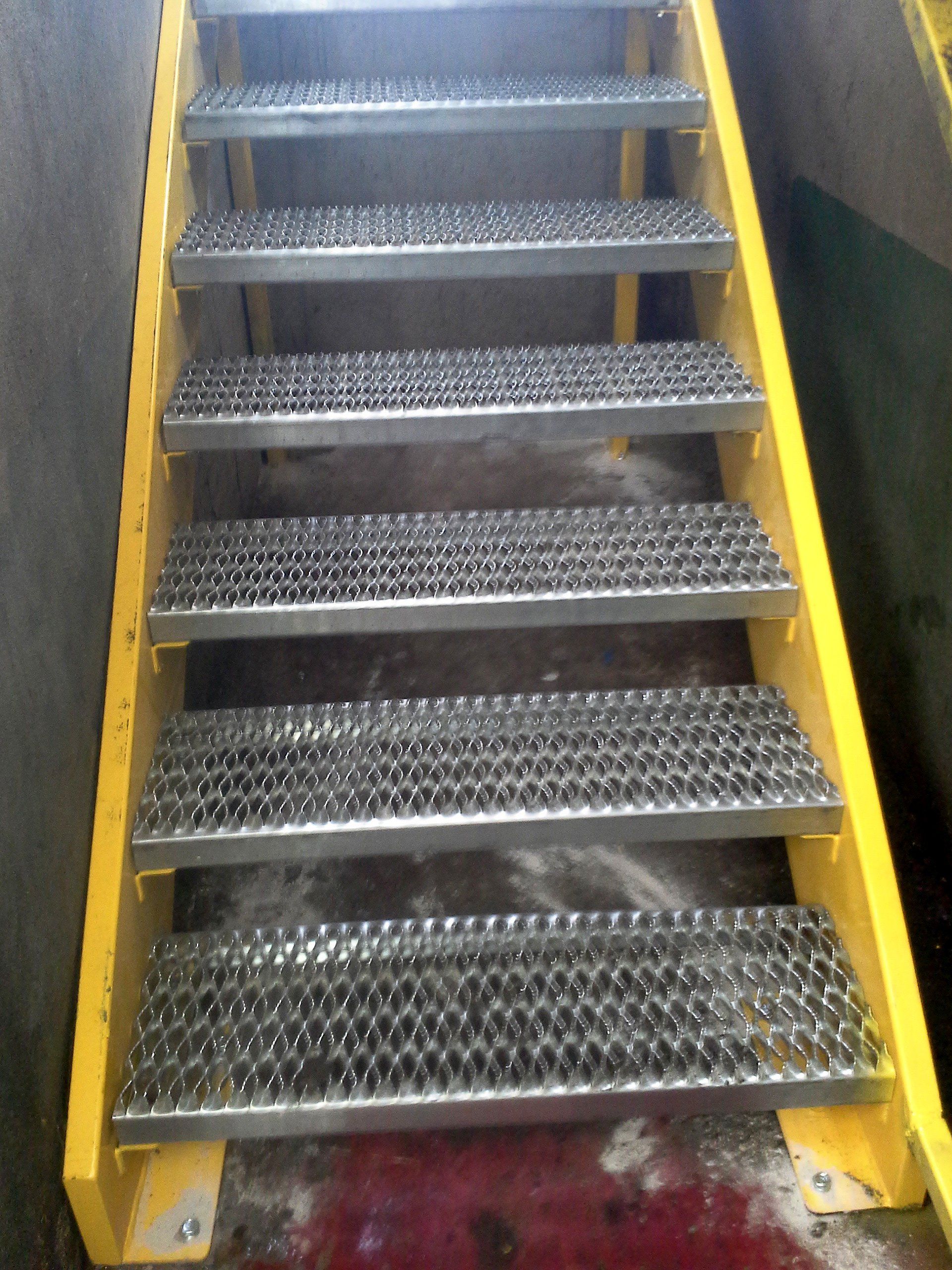 A set of metal stairs with a yellow railing