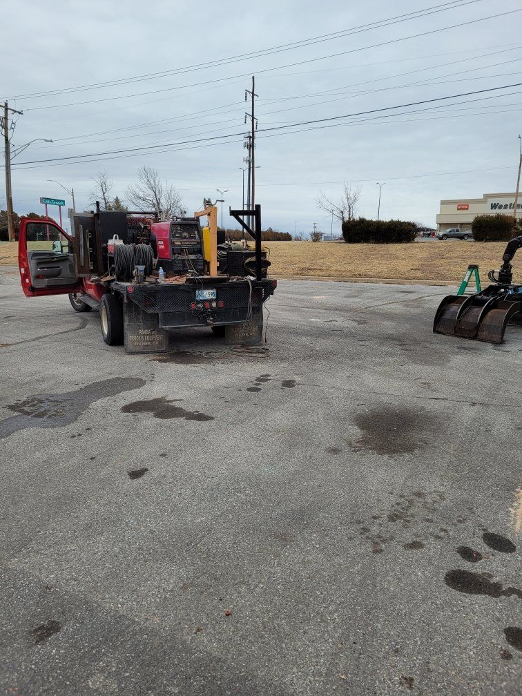 A truck is parked in a parking lot next to a tractor.
