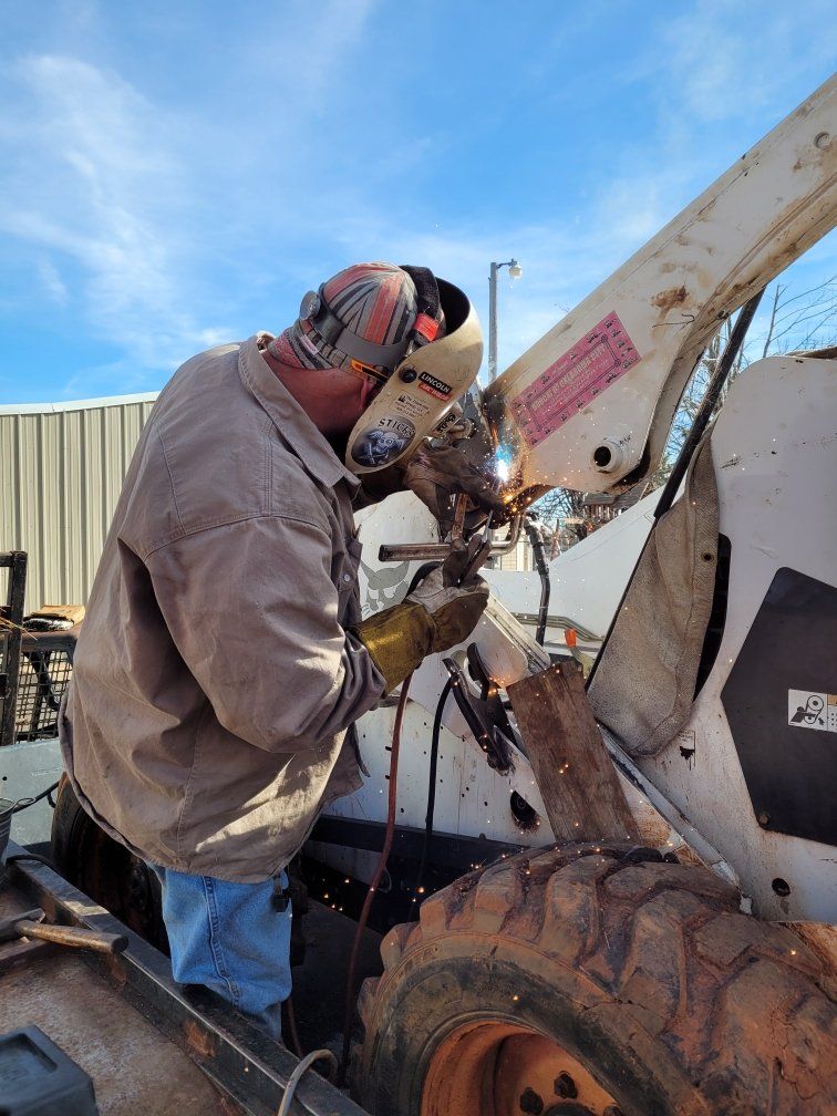A man is welding a piece of metal on a vehicle.