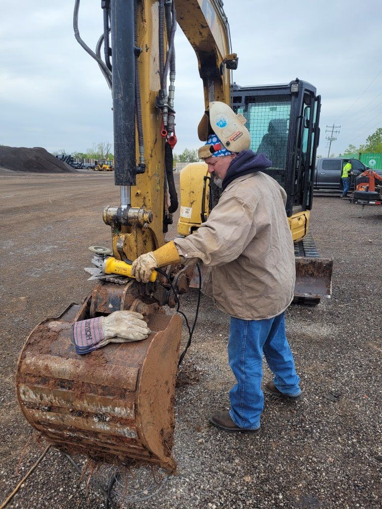A man is working on a bulldozer in a dirt field.