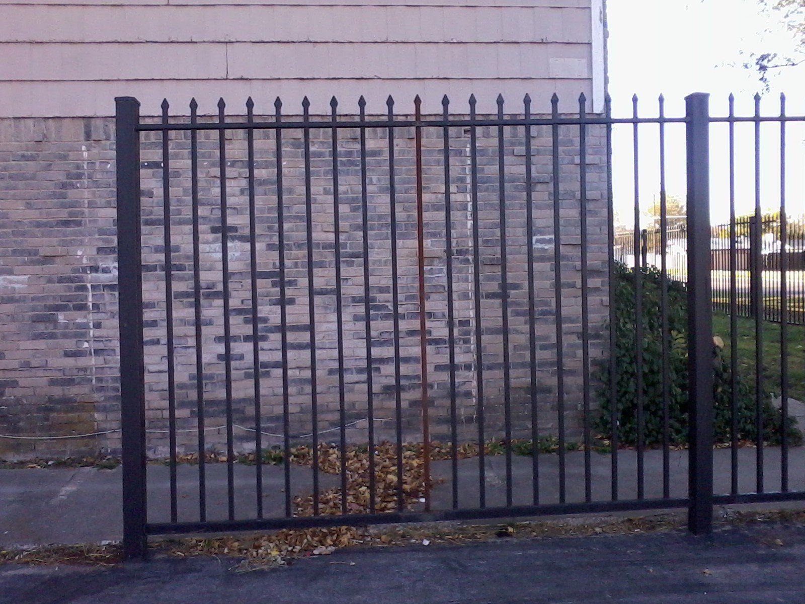 A brick wall with a black fence in front of it
