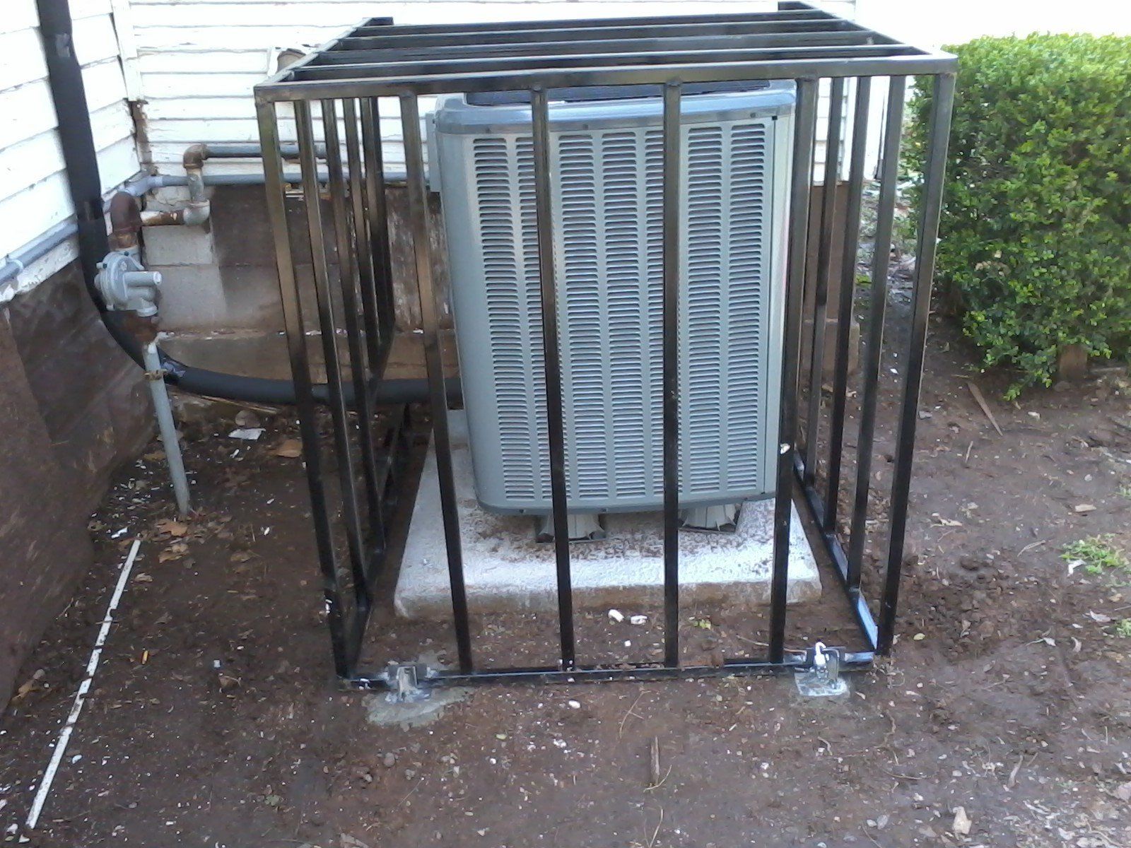 An air conditioner in a cage outside of a house
