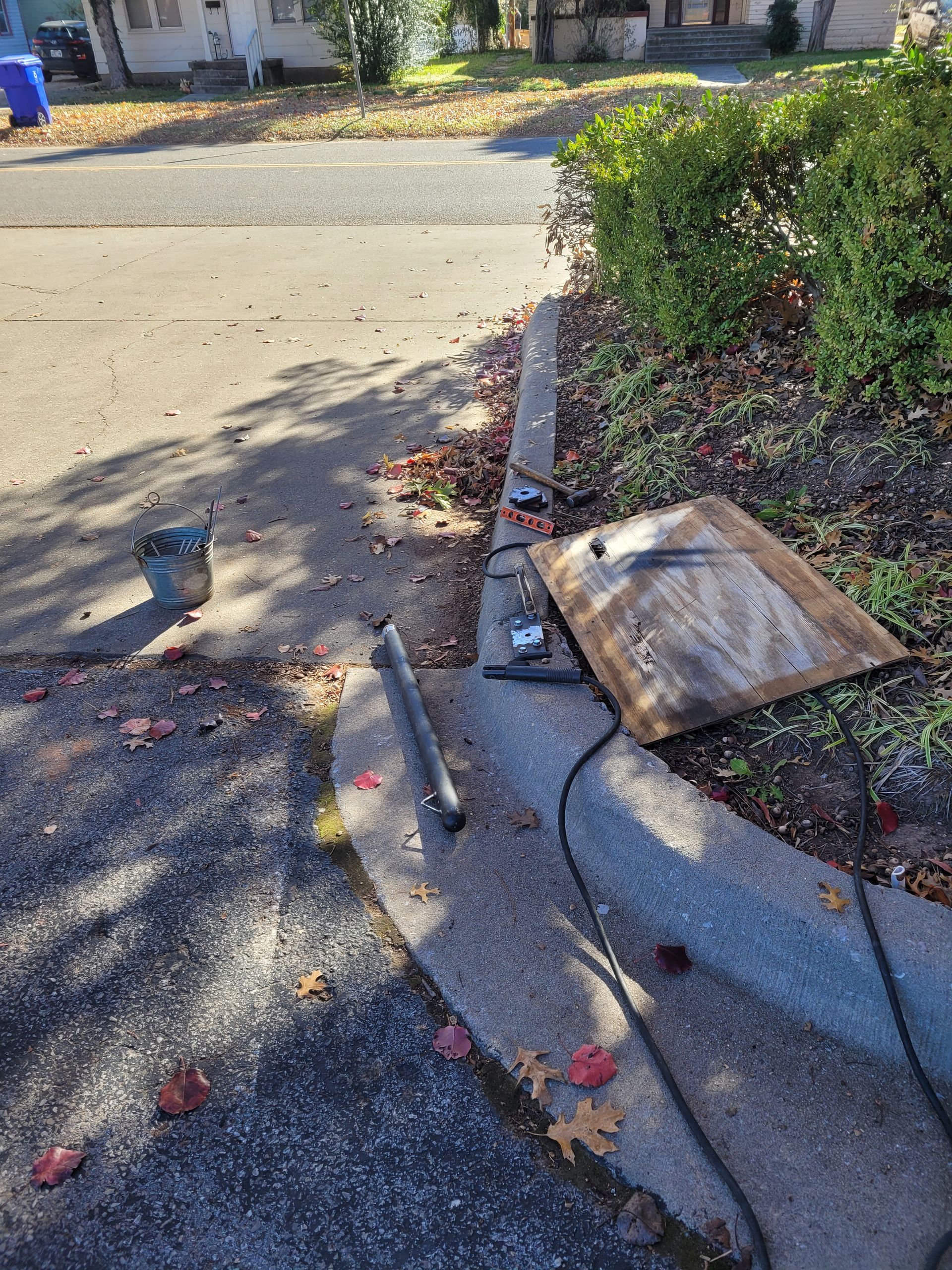 A piece of wood is sitting on the side of the road next to a concrete curb.
