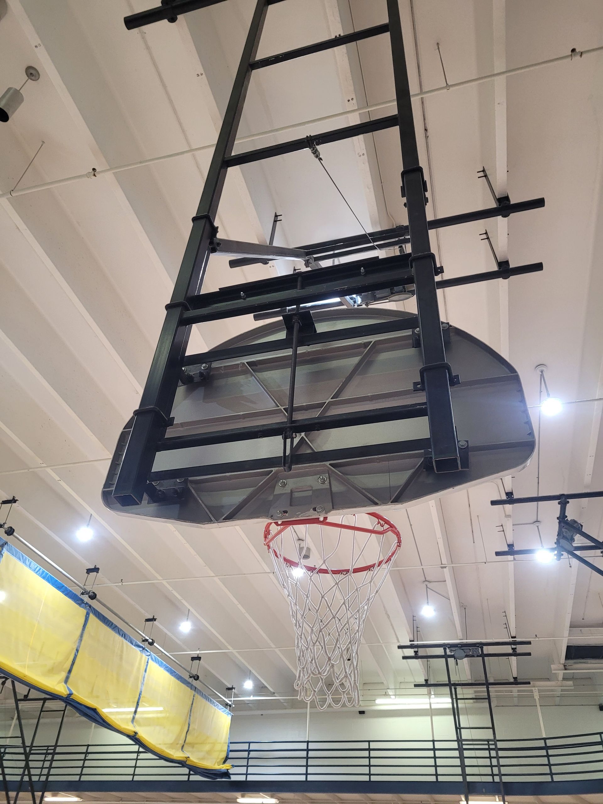 A basketball hoop is hanging from the ceiling of a gym