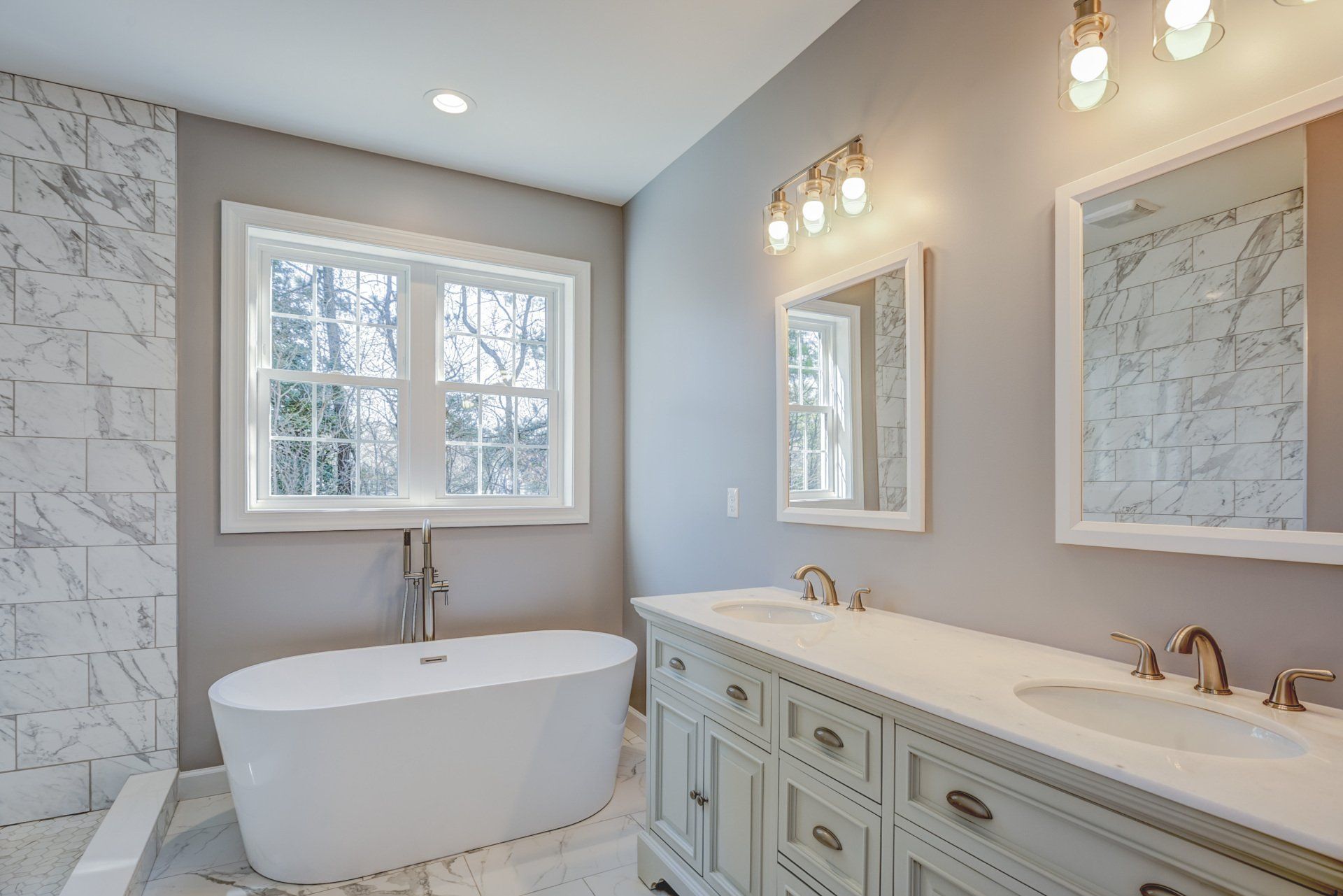 A bathroom with two sinks , a tub , and two mirrors.