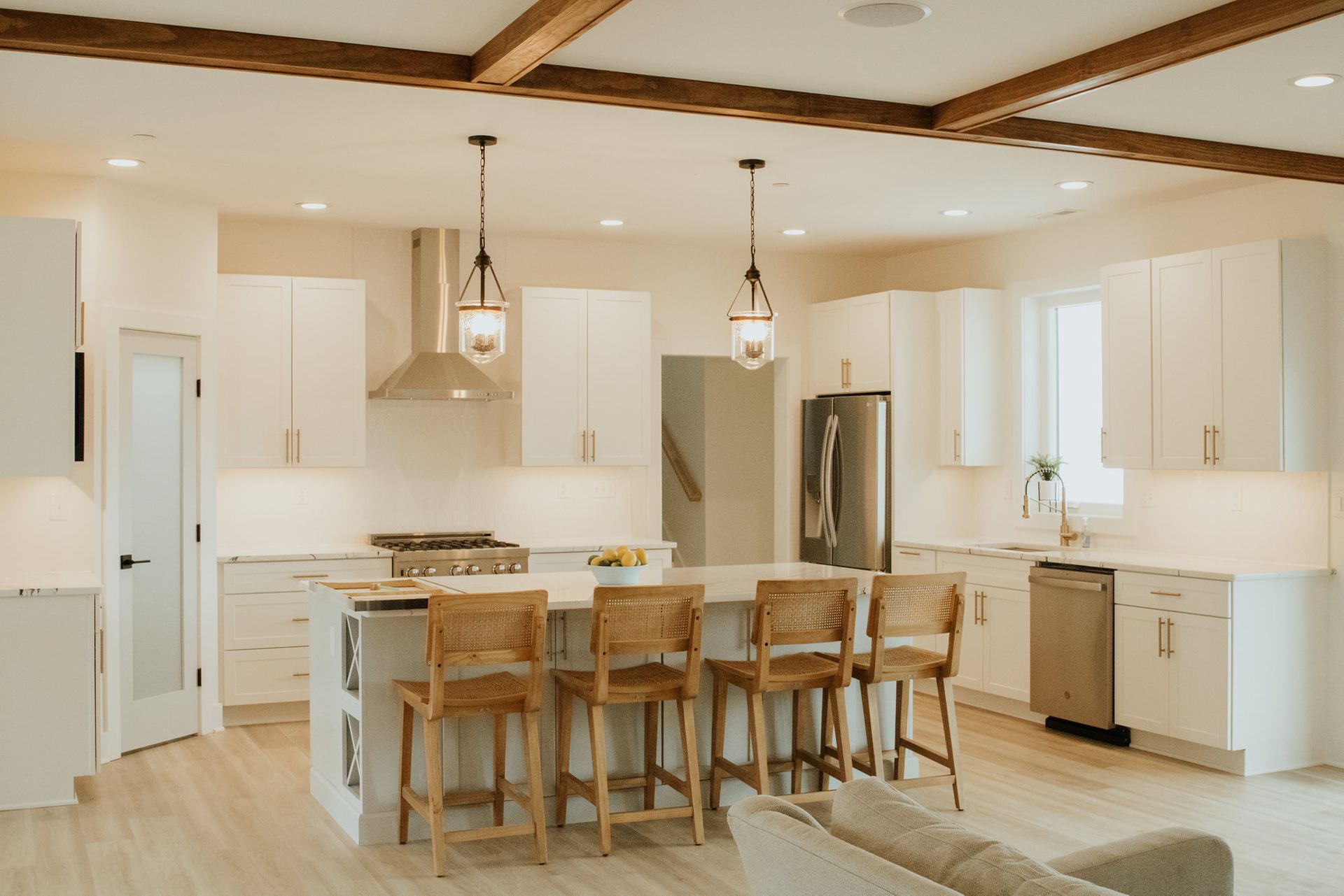 A kitchen with white cabinets , stainless steel appliances , and a large island.