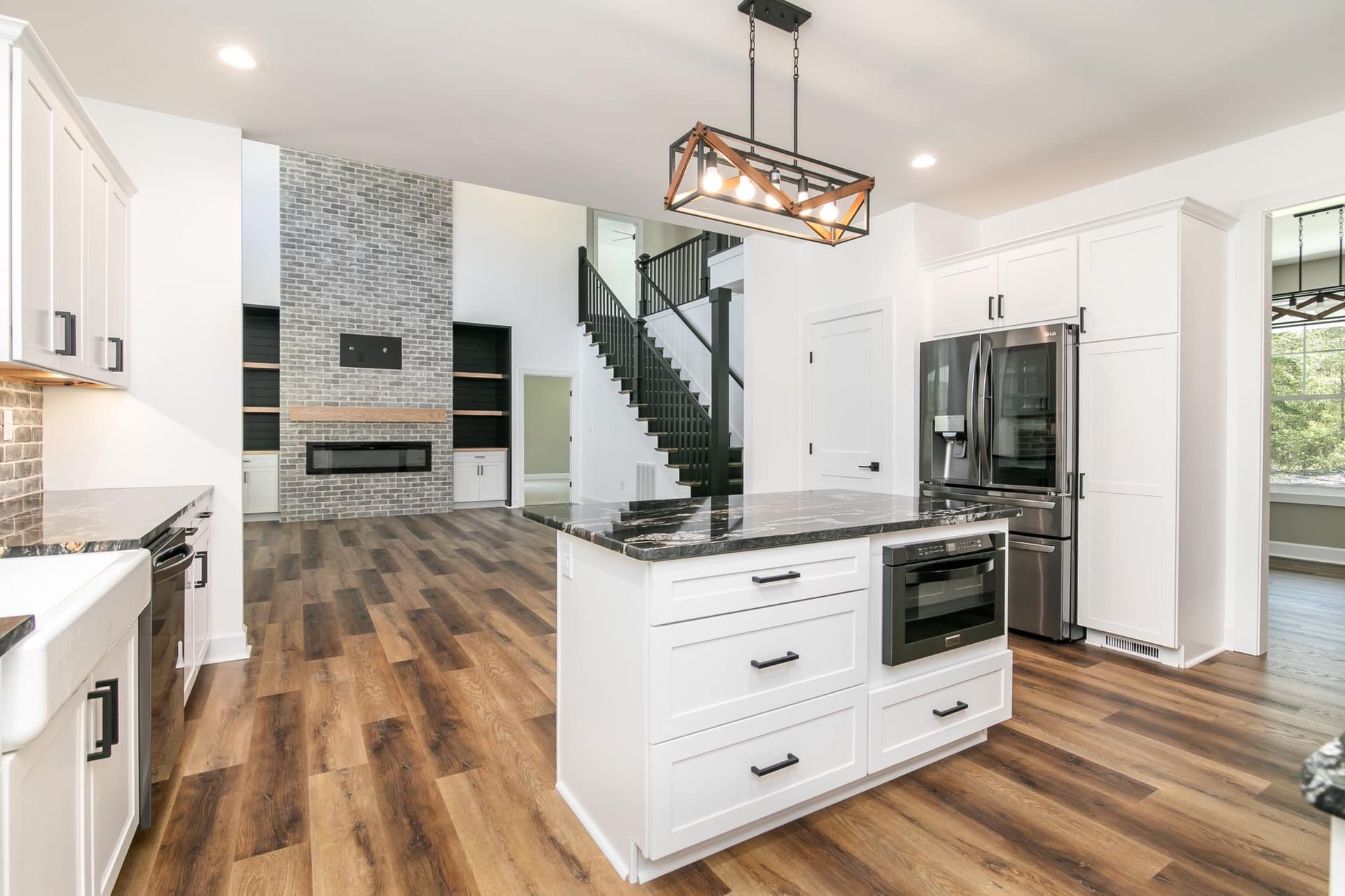 A kitchen with white cabinets , stainless steel appliances , hardwood floors and a large island.