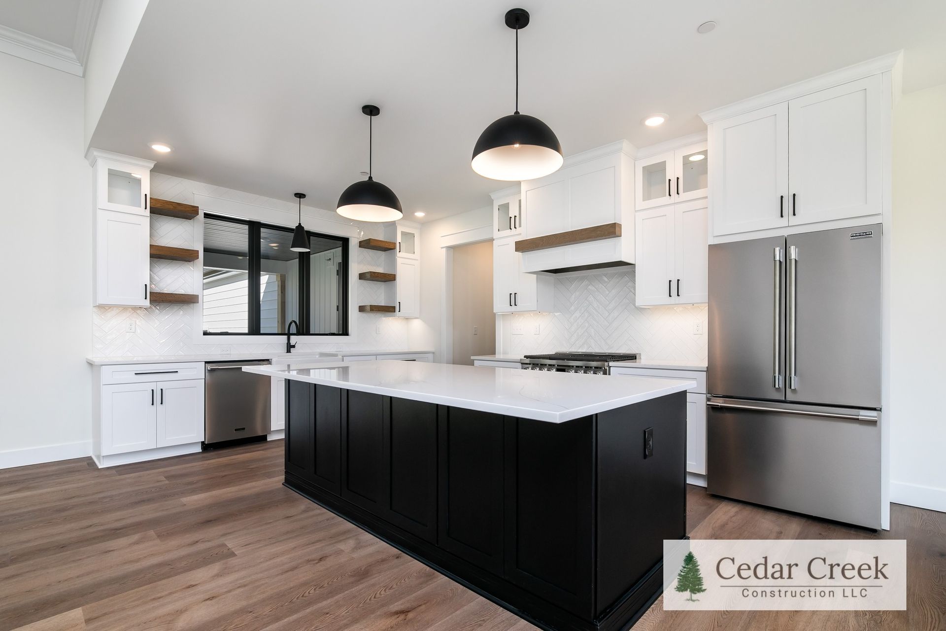 A kitchen with black cabinets, white cabinets, stainless steel appliances and a large island