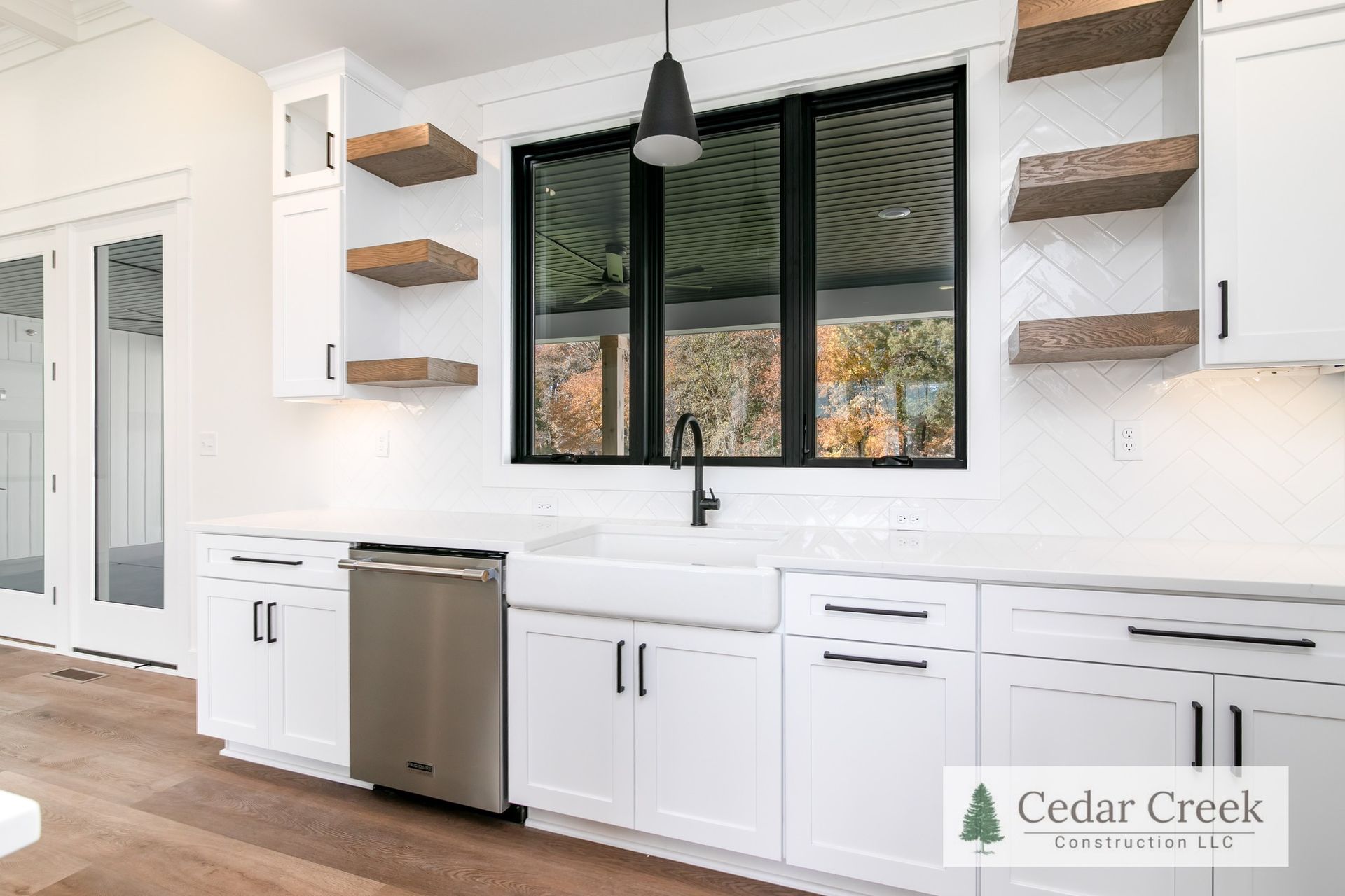 A kitchen with white cabinets, stainless steel appliances, and a large window