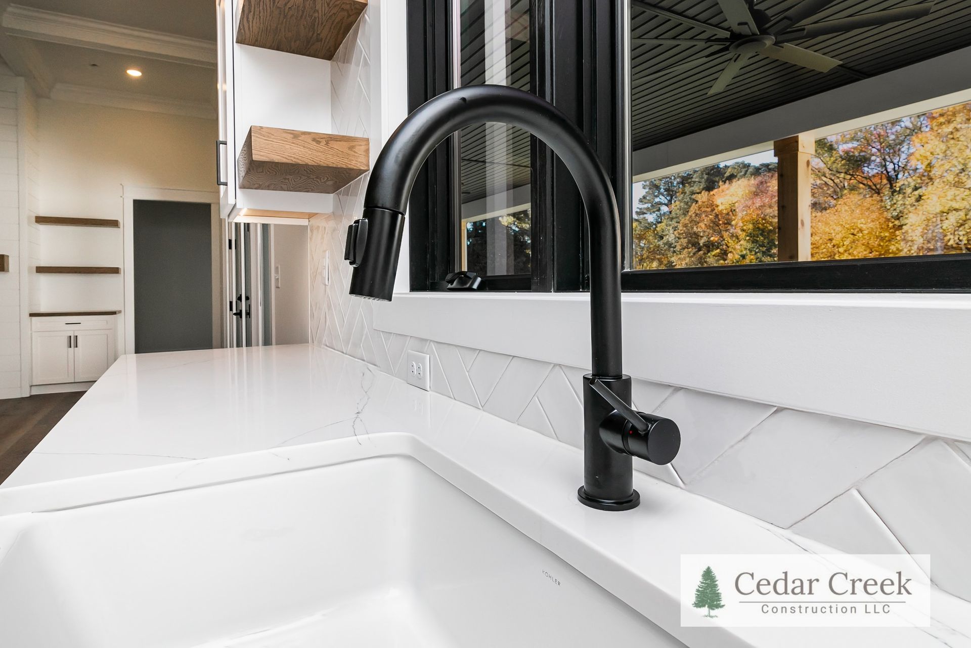 A kitchen sink with a black faucet and a window