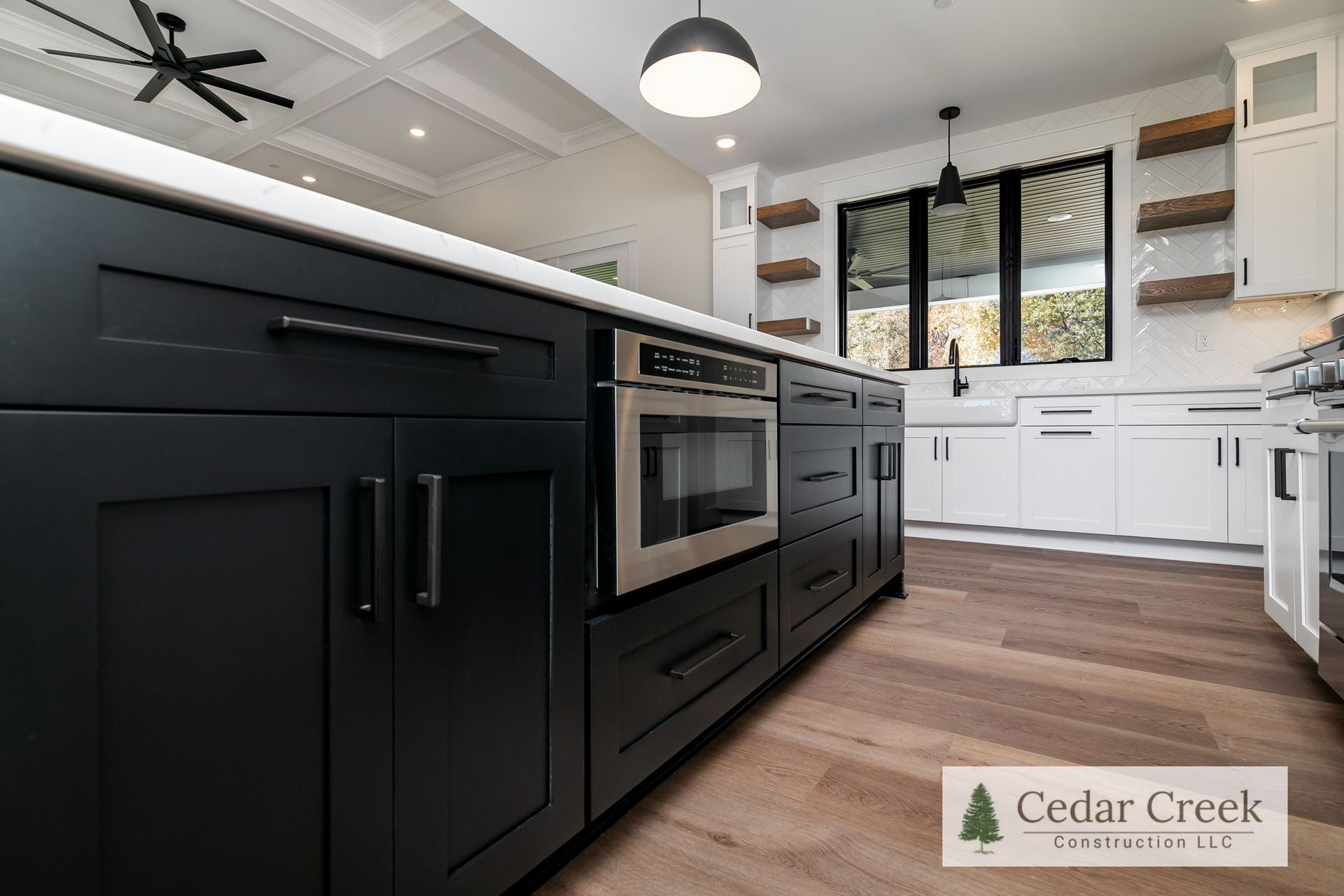 A kitchen with black cabinets, white cabinets, and stainless steel appliances