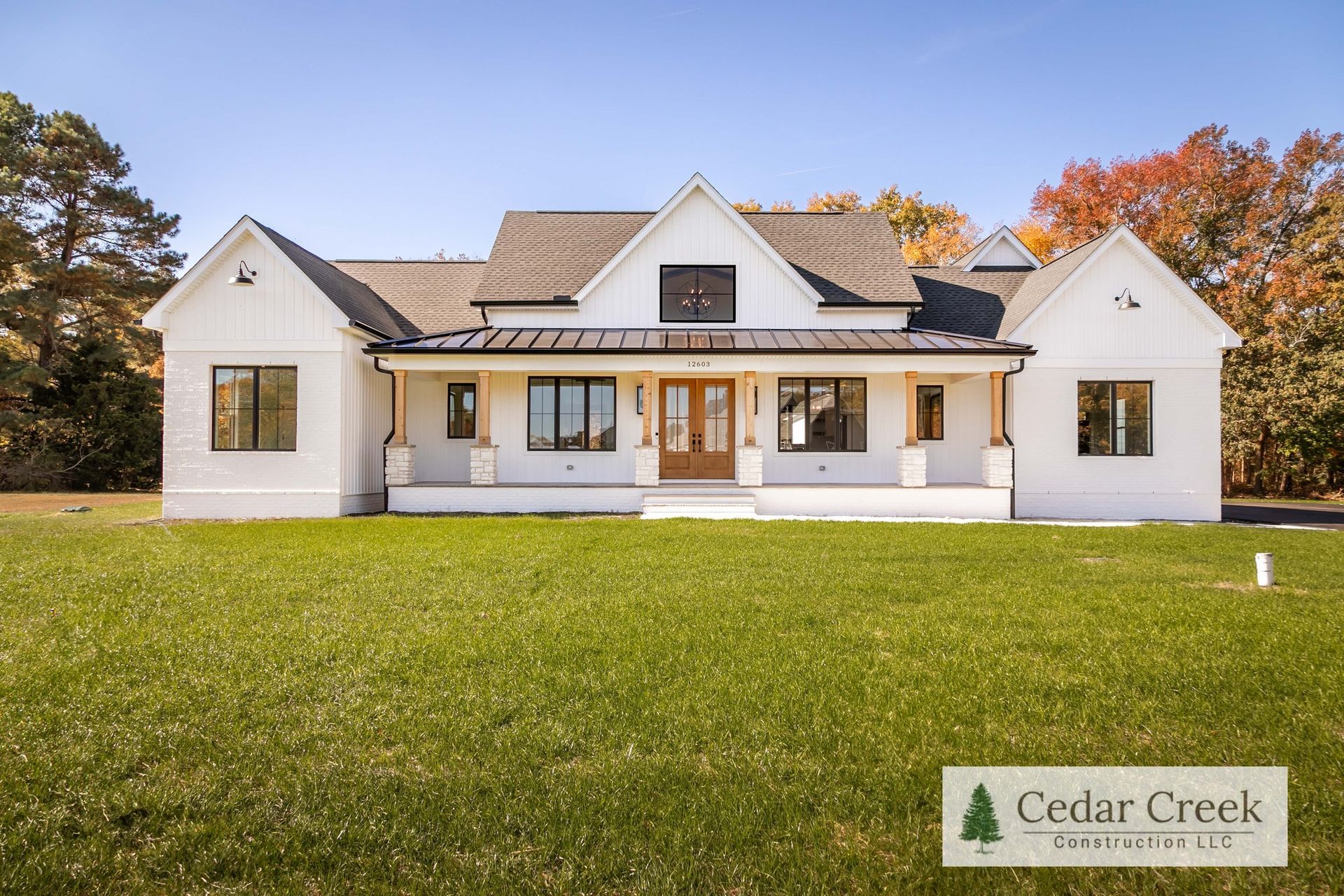 A large white house is sitting on top of a lush green field