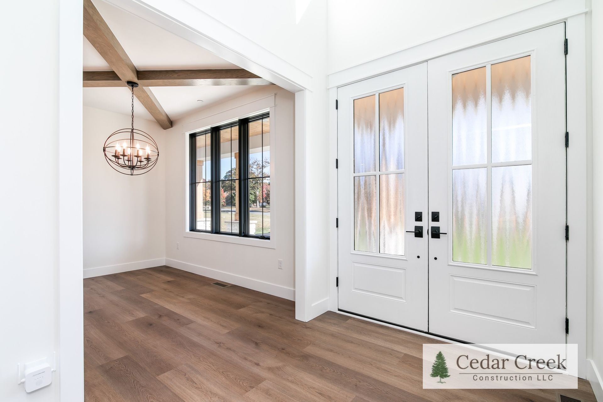 An empty room with hardwood floors and a chandelier