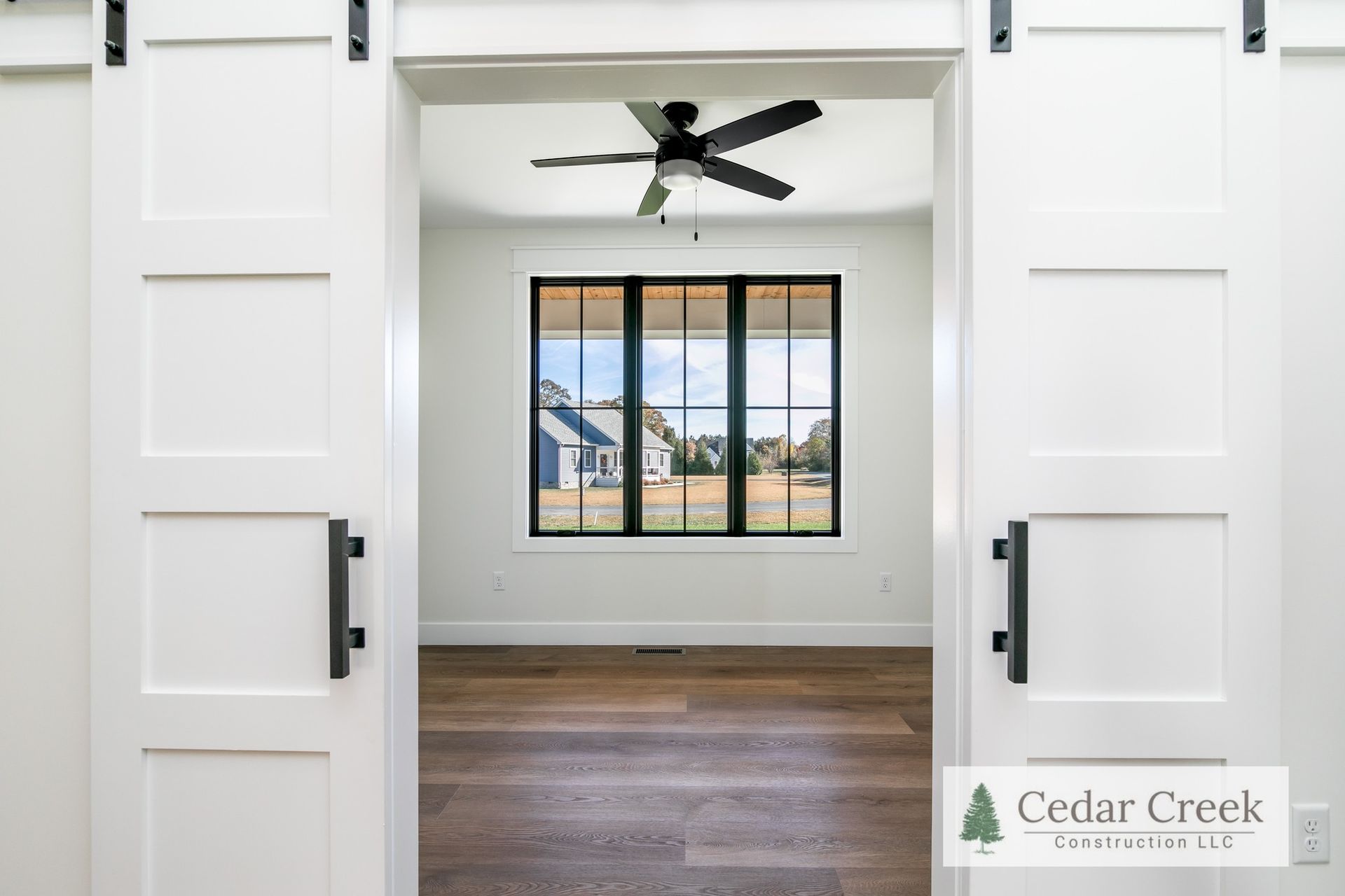 A bedroom with sliding barn doors and a ceiling fan