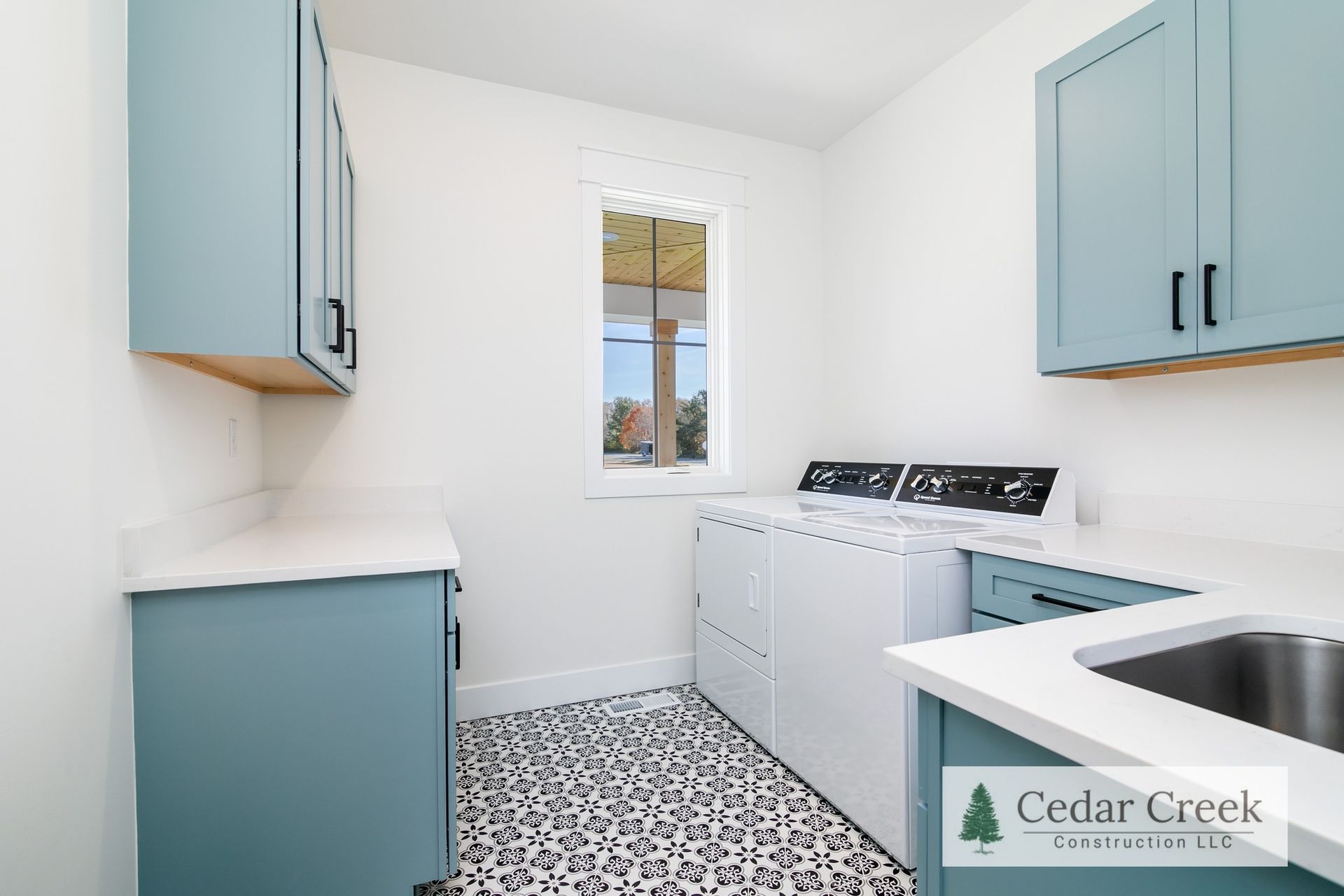A laundry room with blue cabinets, a washer and dryer, and a sink